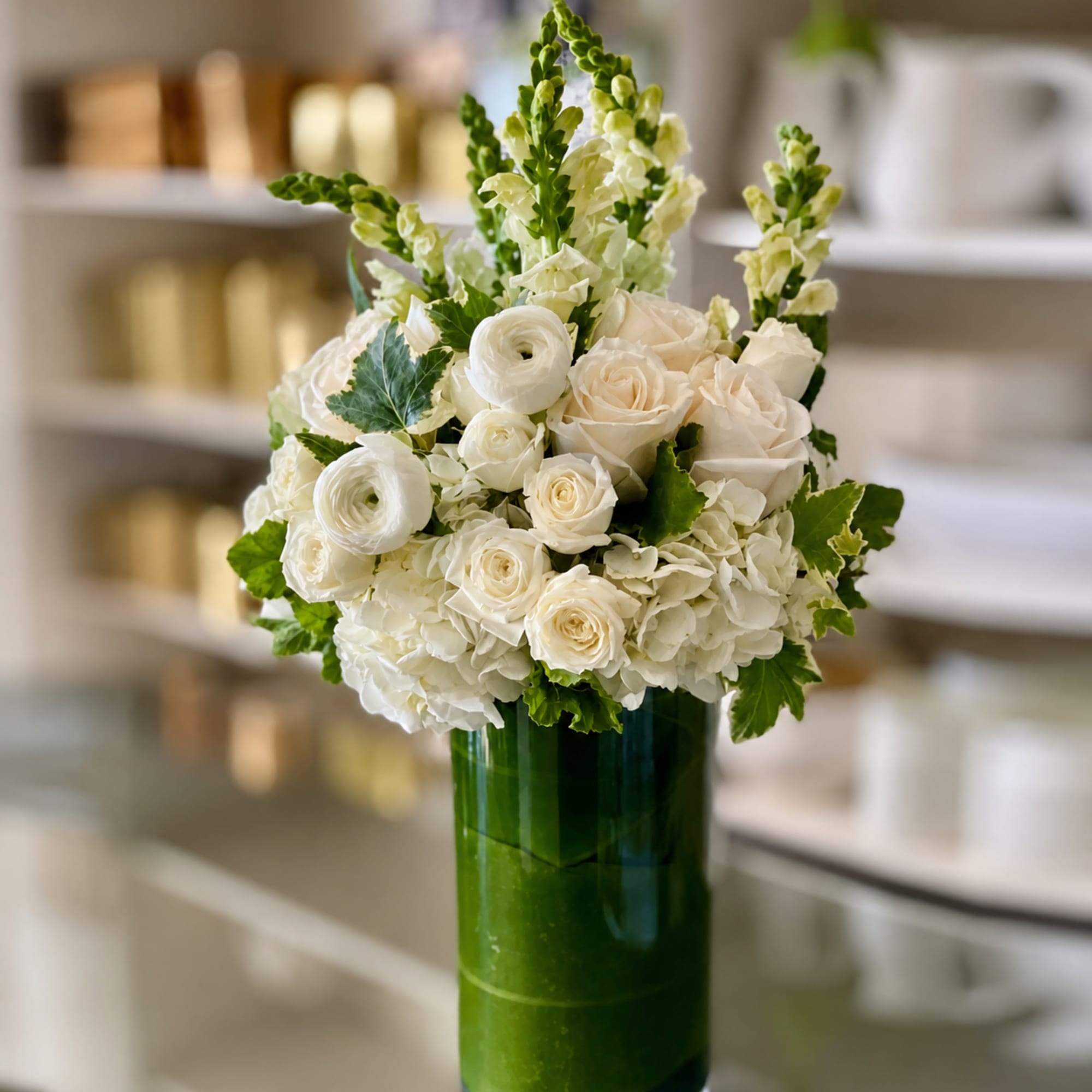 White roses and ranunculus in a tall green glass vase, photo 2 of 3