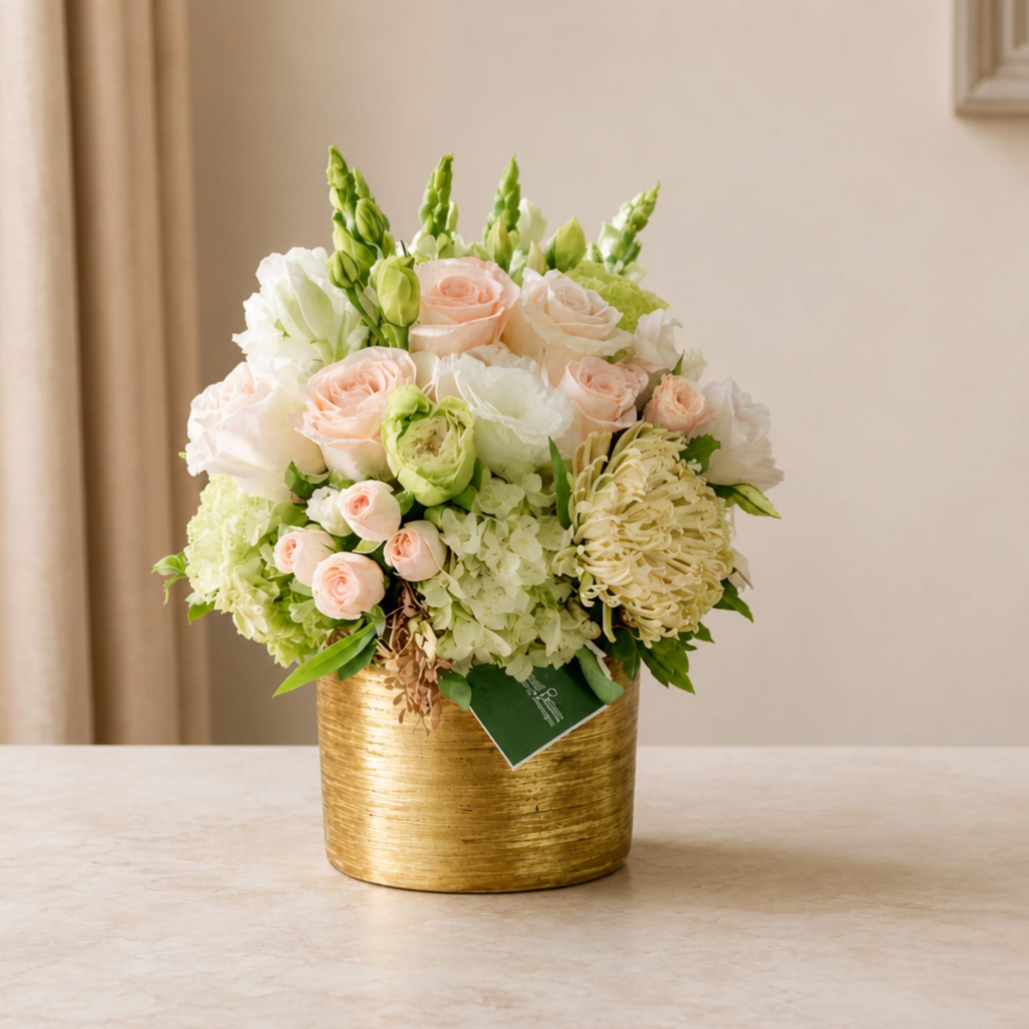 Peach and white flower arrangement in a gold vase