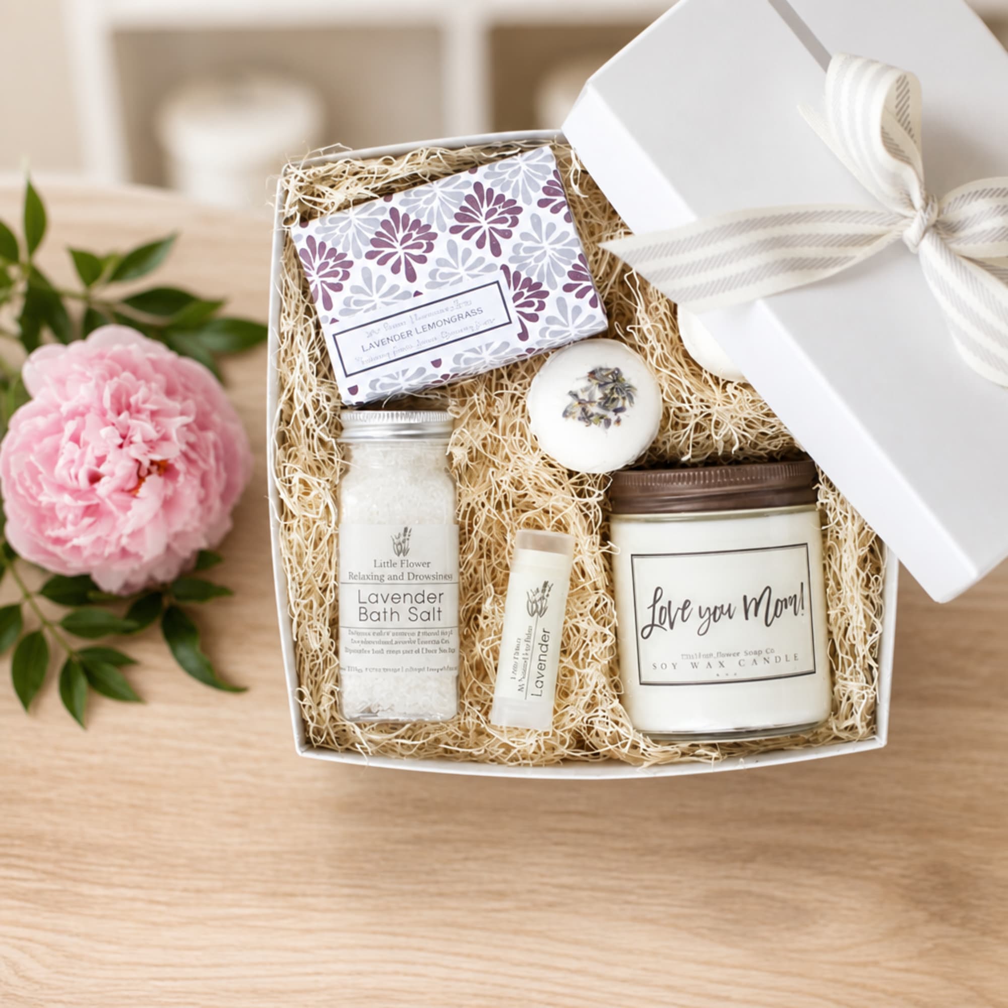 Gift box with lavender bath items and a pink peony beside it