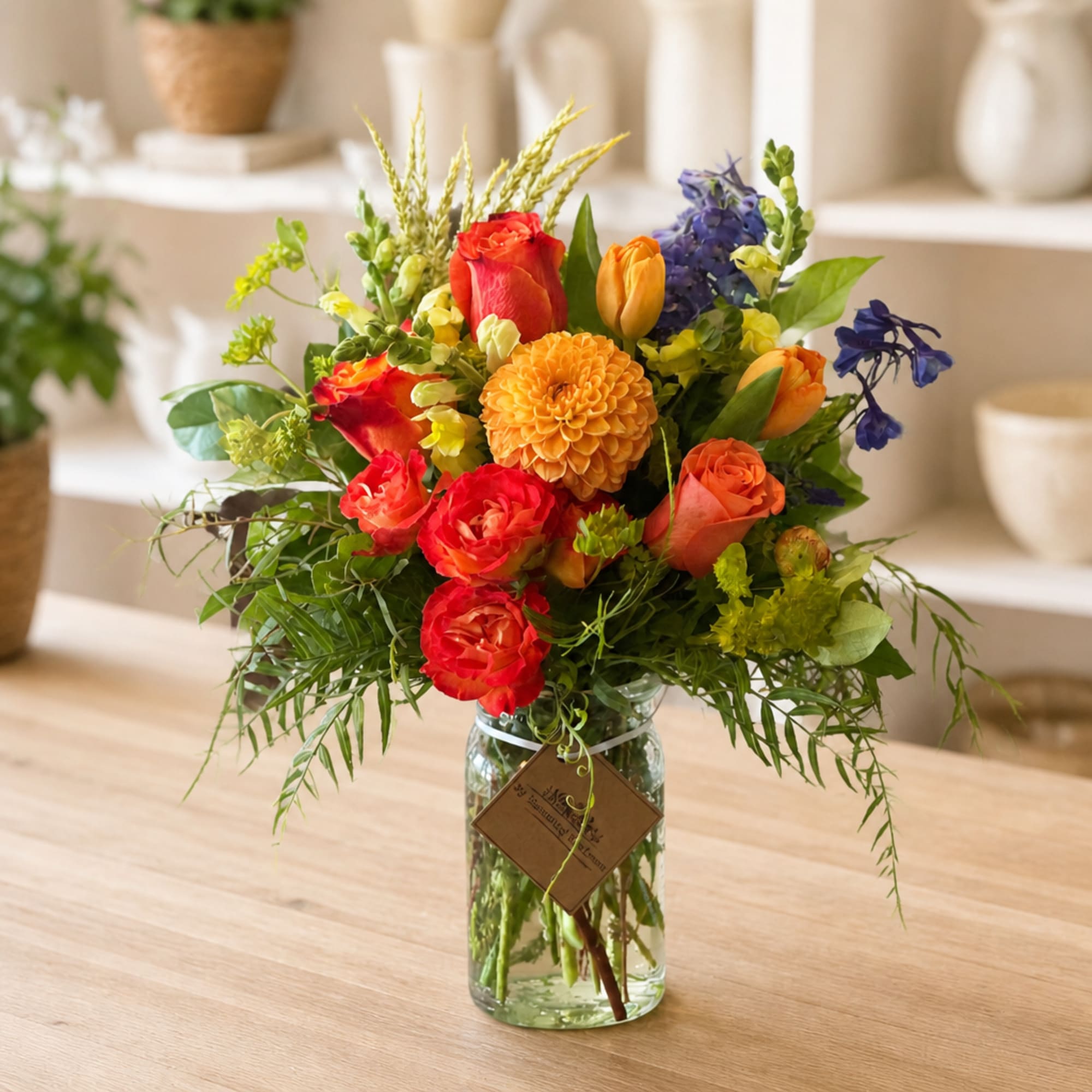 Mixed bouquet of roses, tulips, and a dahlia in a glass jar vase