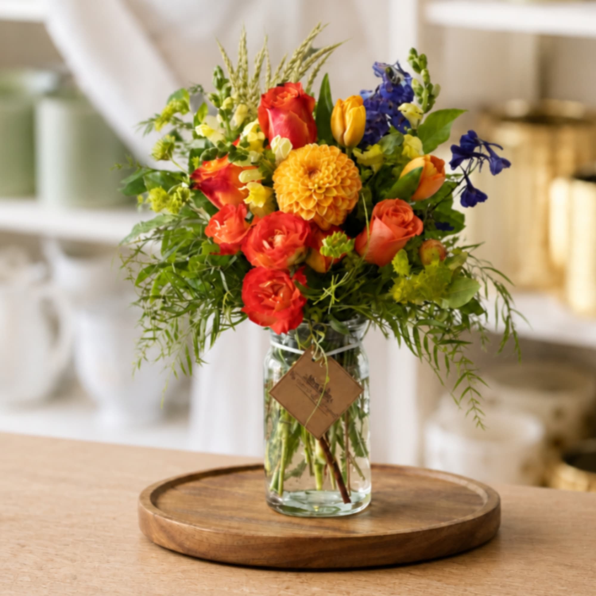 Colorful mixed bouquet in a clear glass vase on a wooden tray