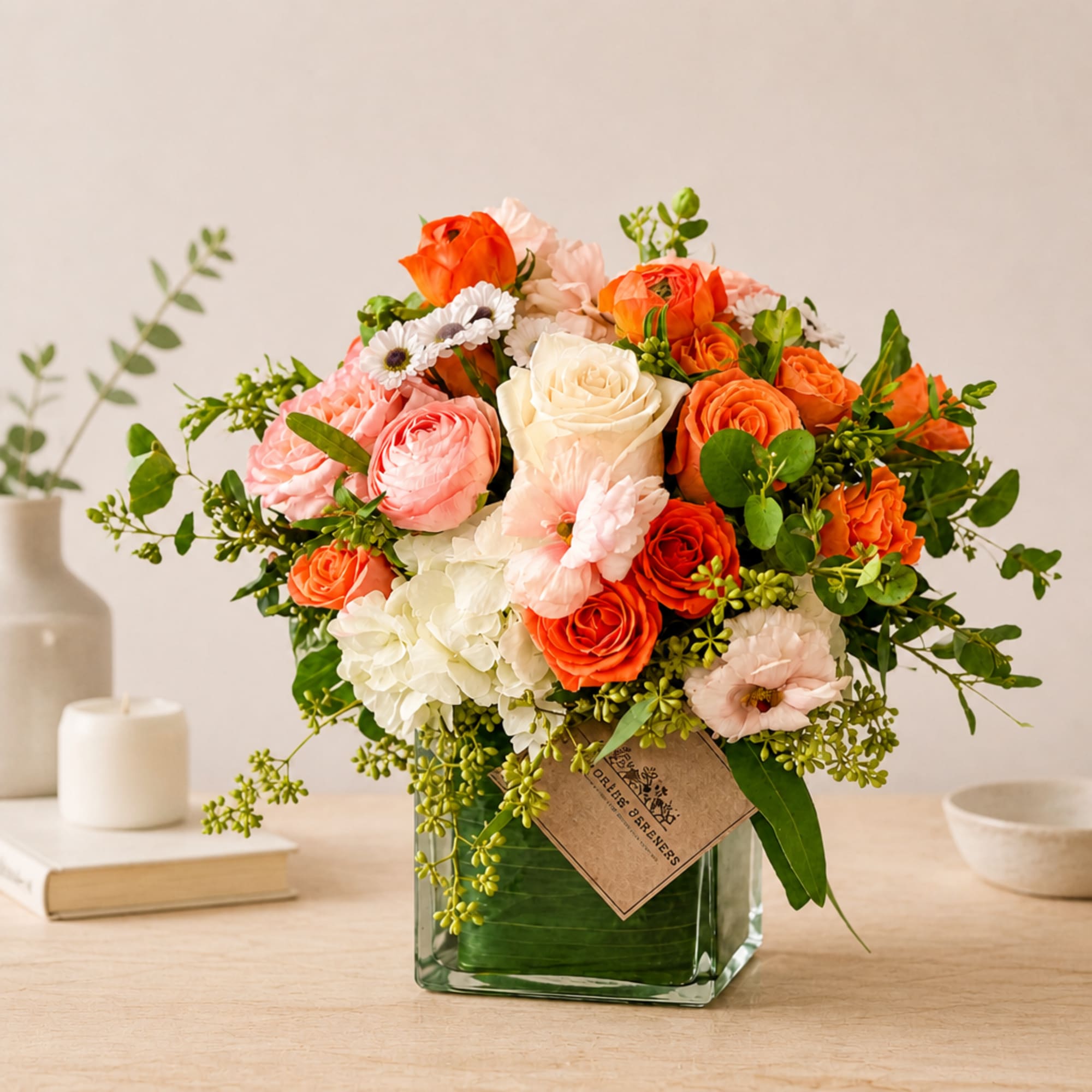 Mixed bouquet of orange, pink, and white flowers in a glass vase