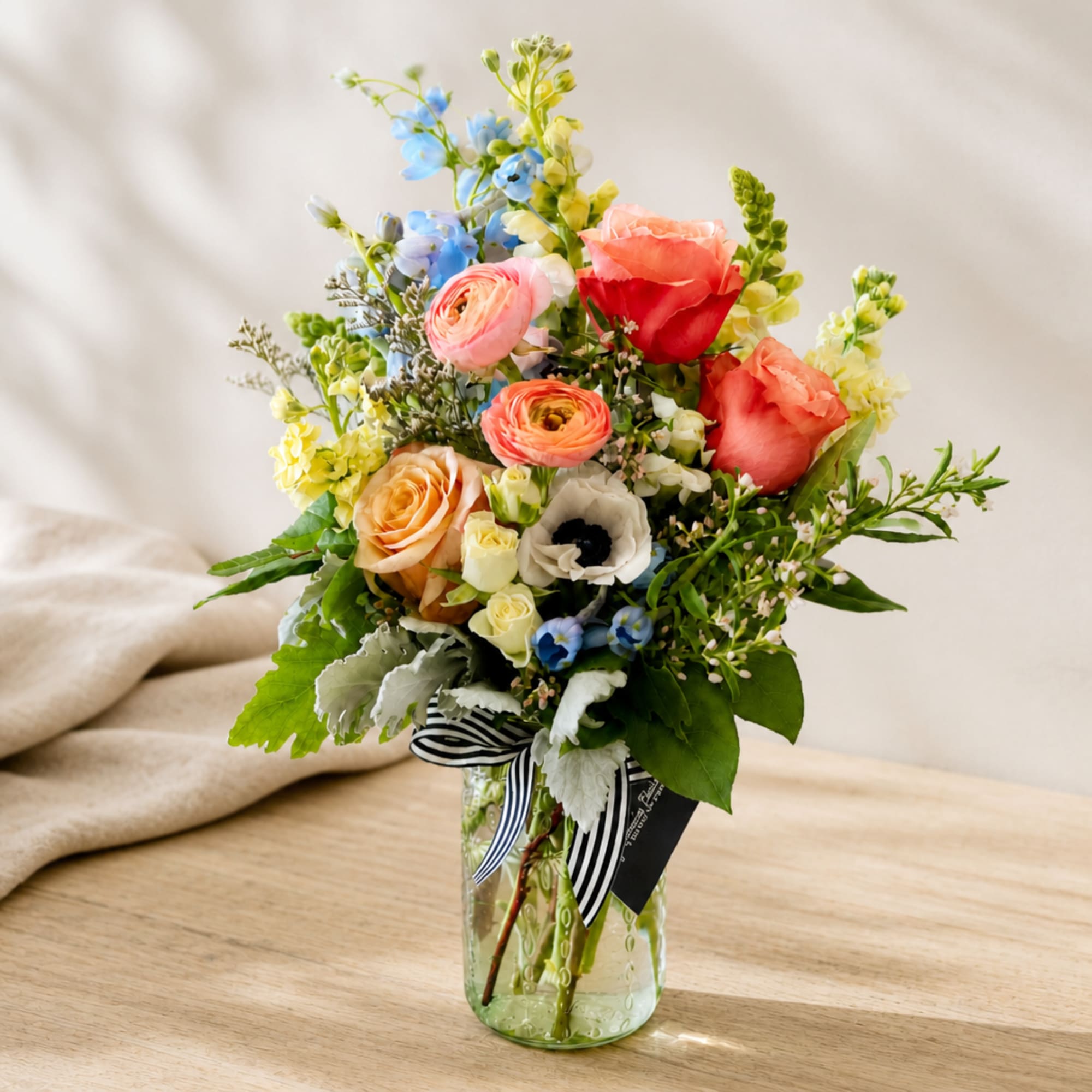 Mixed bouquet of roses, ranunculus, and blue flowers in a glass vase, photo 2 of 2