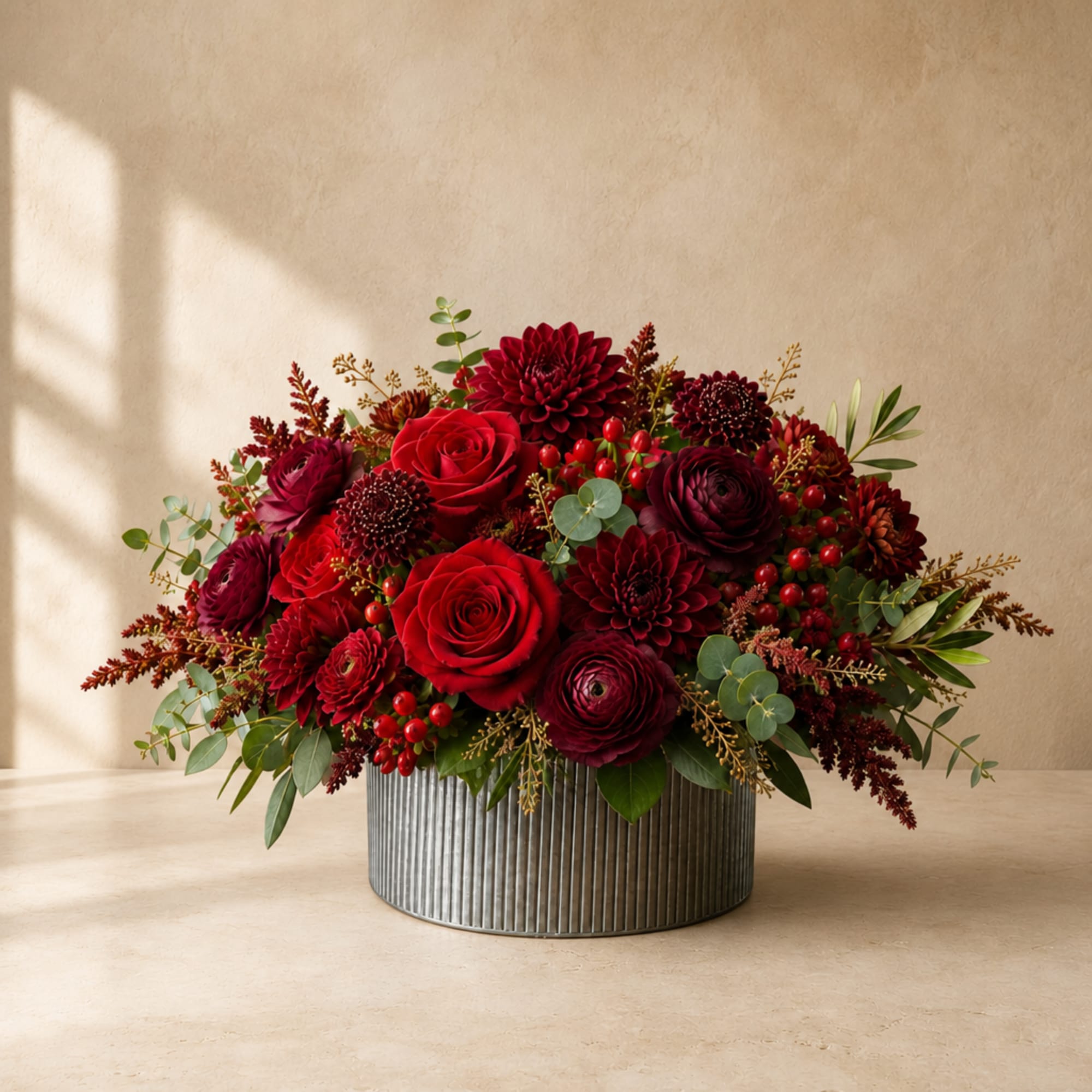 Red roses and burgundy blooms in a ribbed metal container