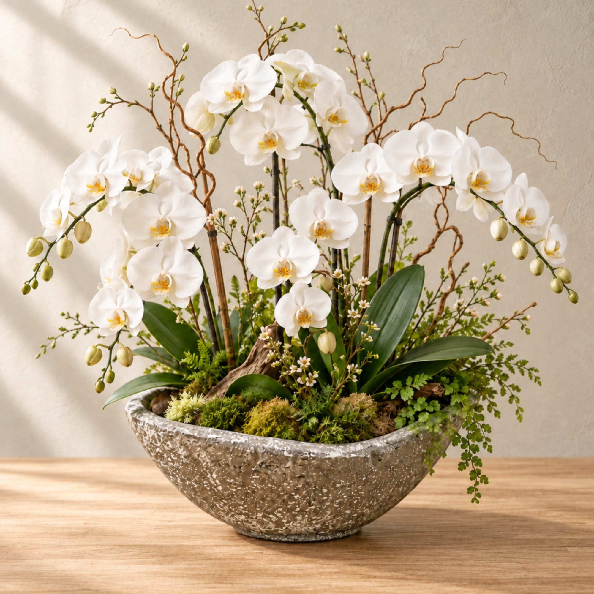 White orchid arrangement in a textured silver bowl vase