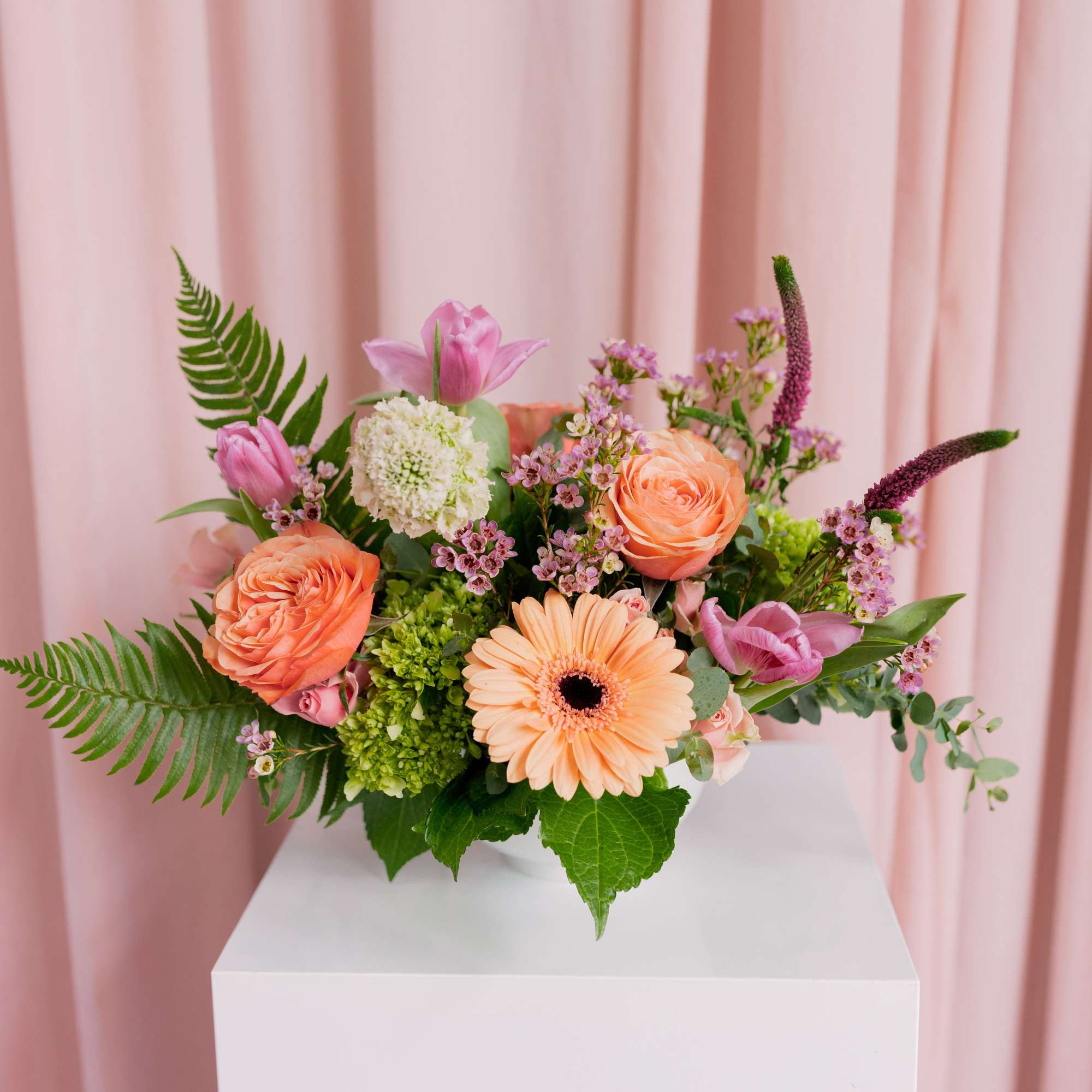 Pink and peach floral arrangement in a white vase