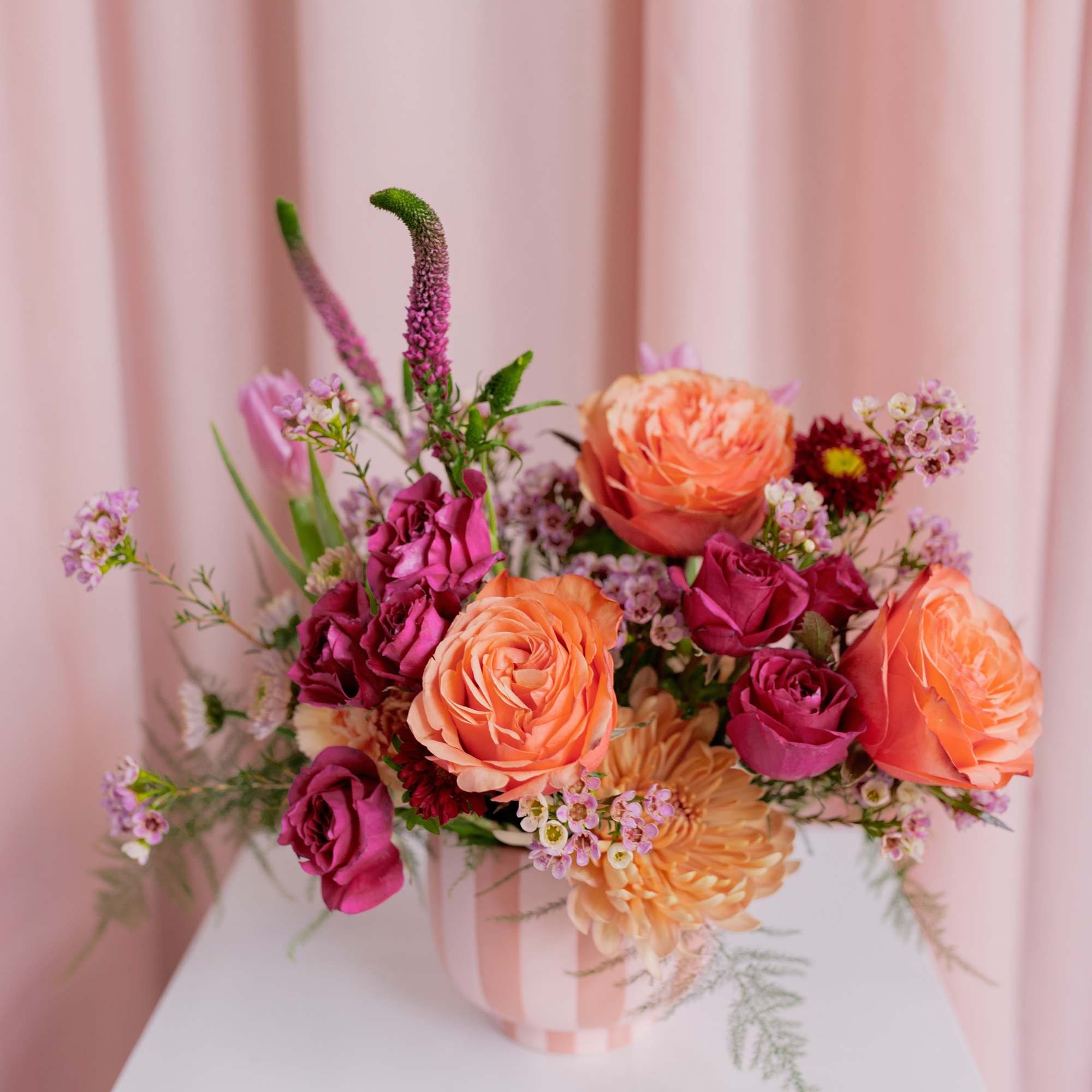 Pink and peach rose bouquet in a striped vase
