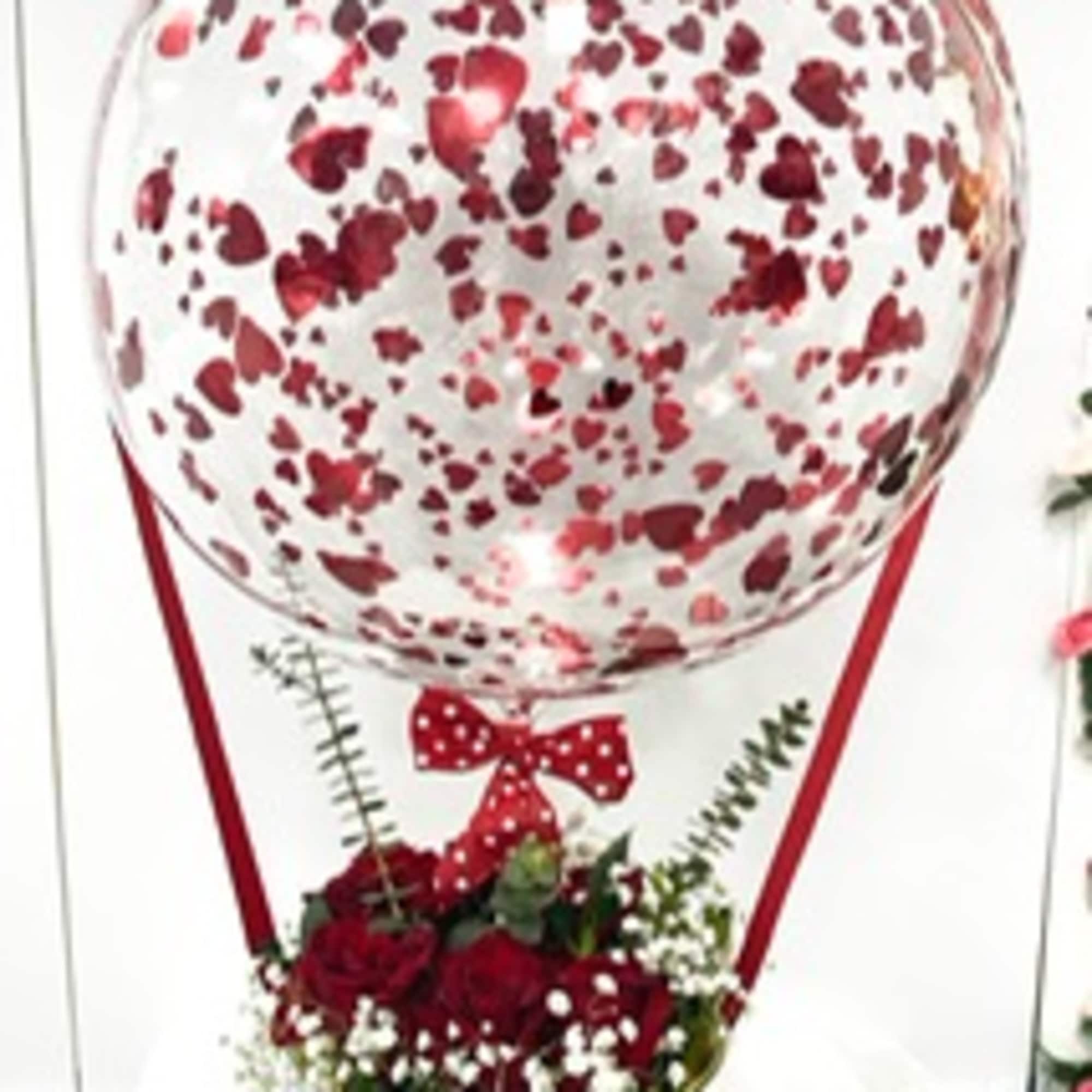 Heart-patterned balloon above a red rose arrangement in a gold vase
