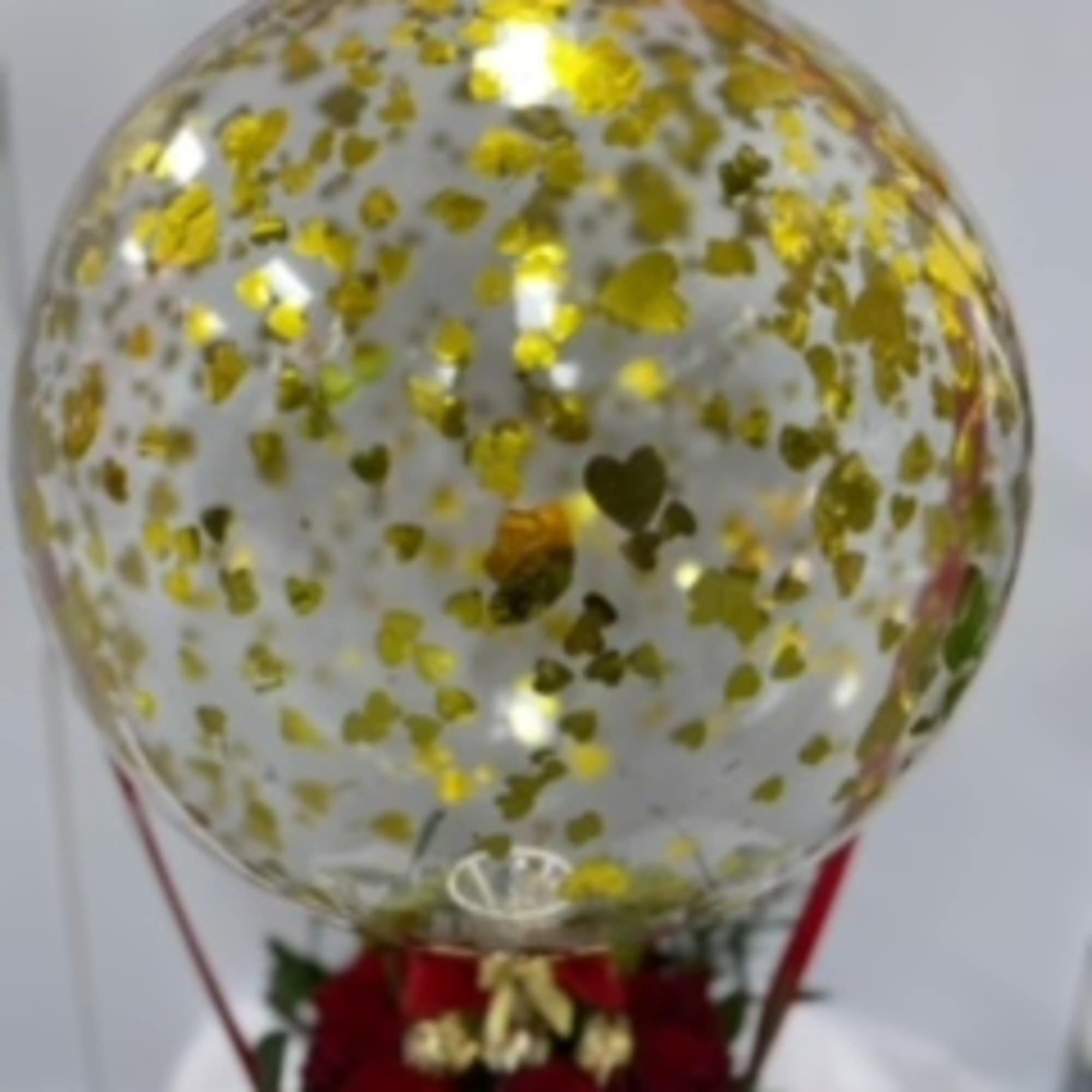 Clear balloon with gold confetti above red roses