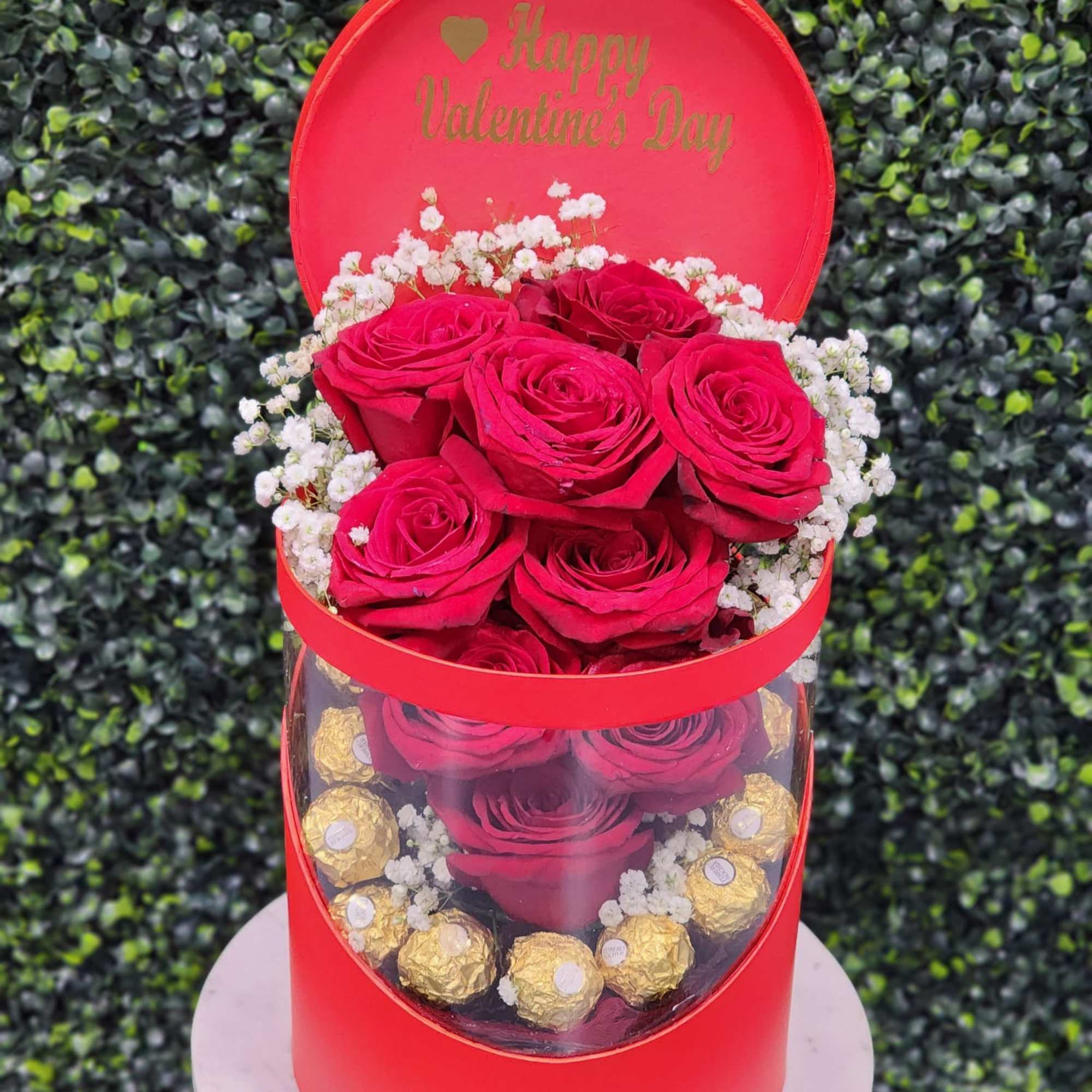 Red roses in a round gift box with chocolates and a Happy Valentine's Day lid