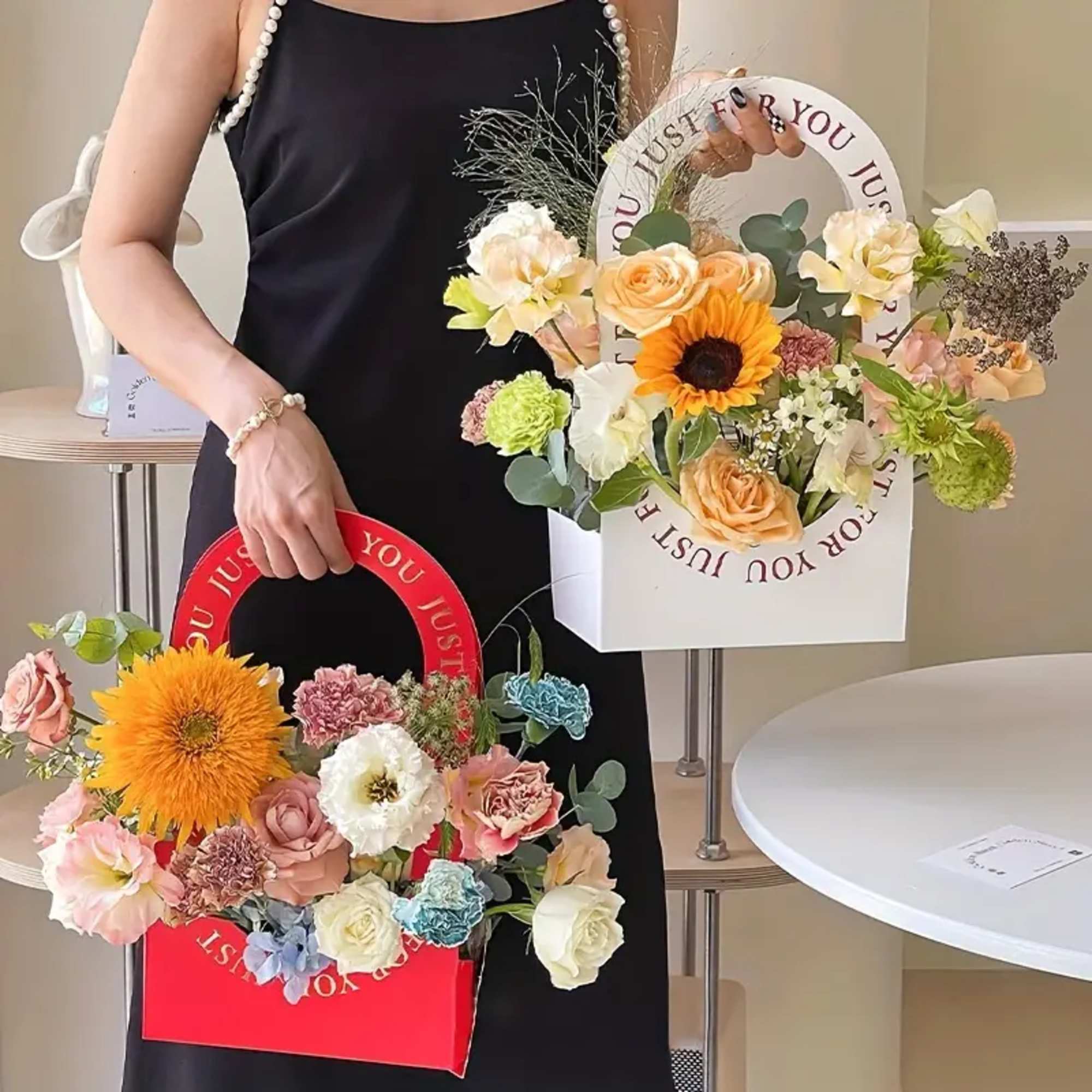 Person holding two flower gift boxes with mixed blooms