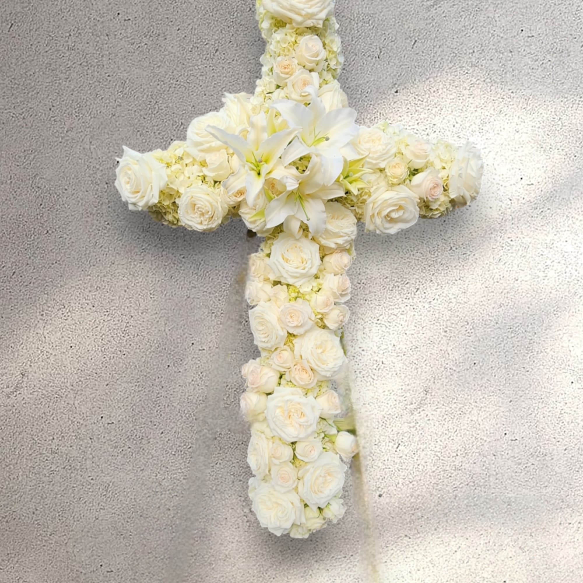 An all white tribute, this white cross funeral spray is pure and