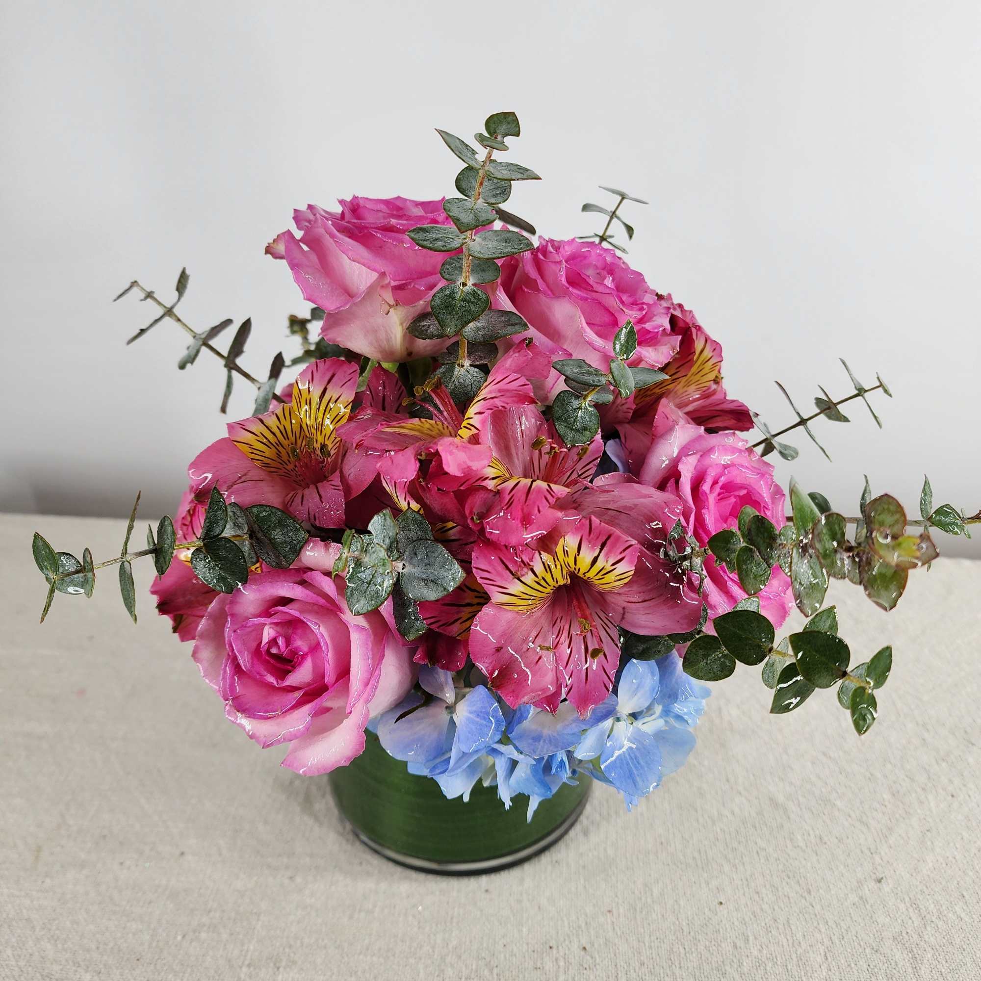 Pink roses and alstroemeria in a green vase with blue hydrangea