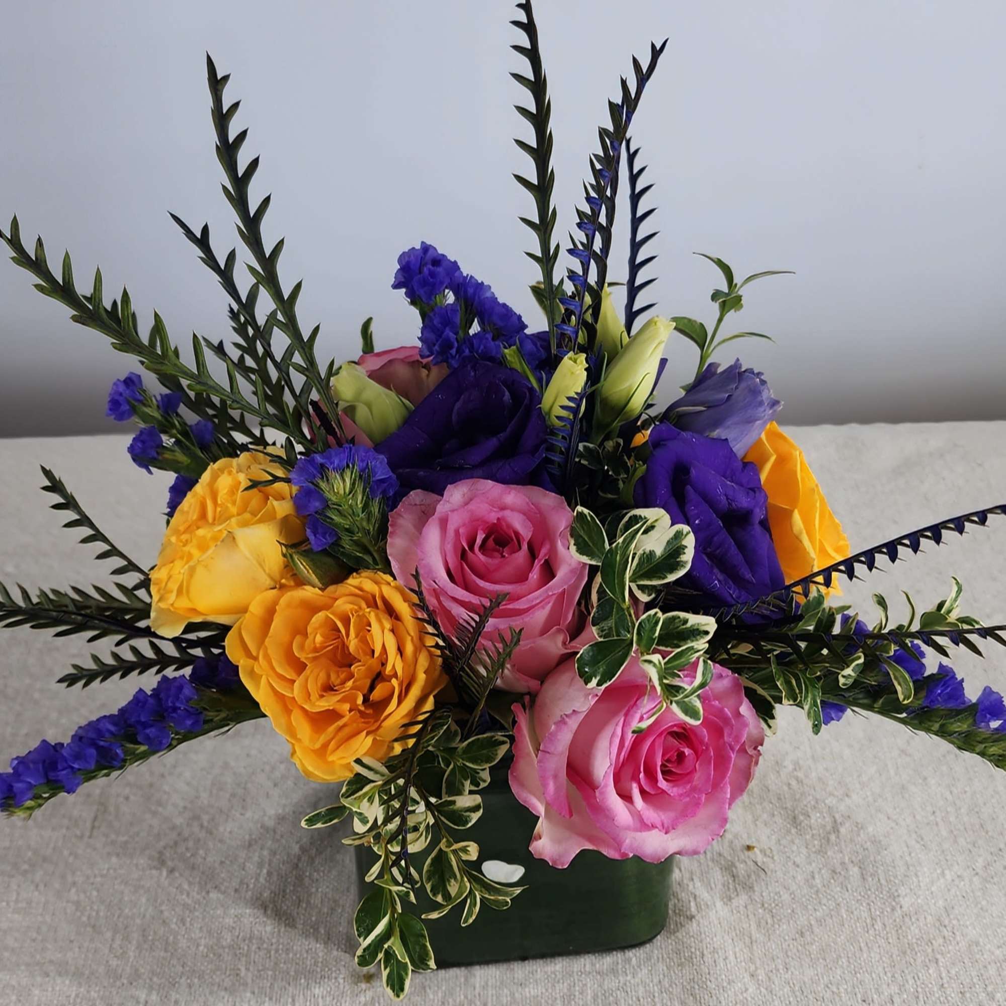 Colorful rose bouquet in a dark green container