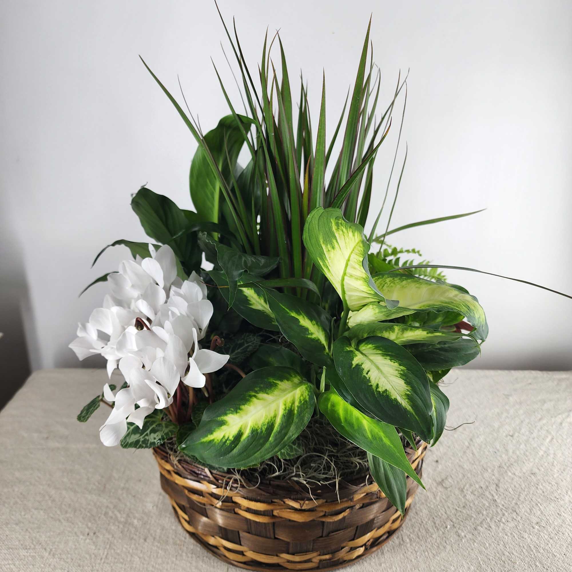 White flowers and green foliage arranged in a wicker basket