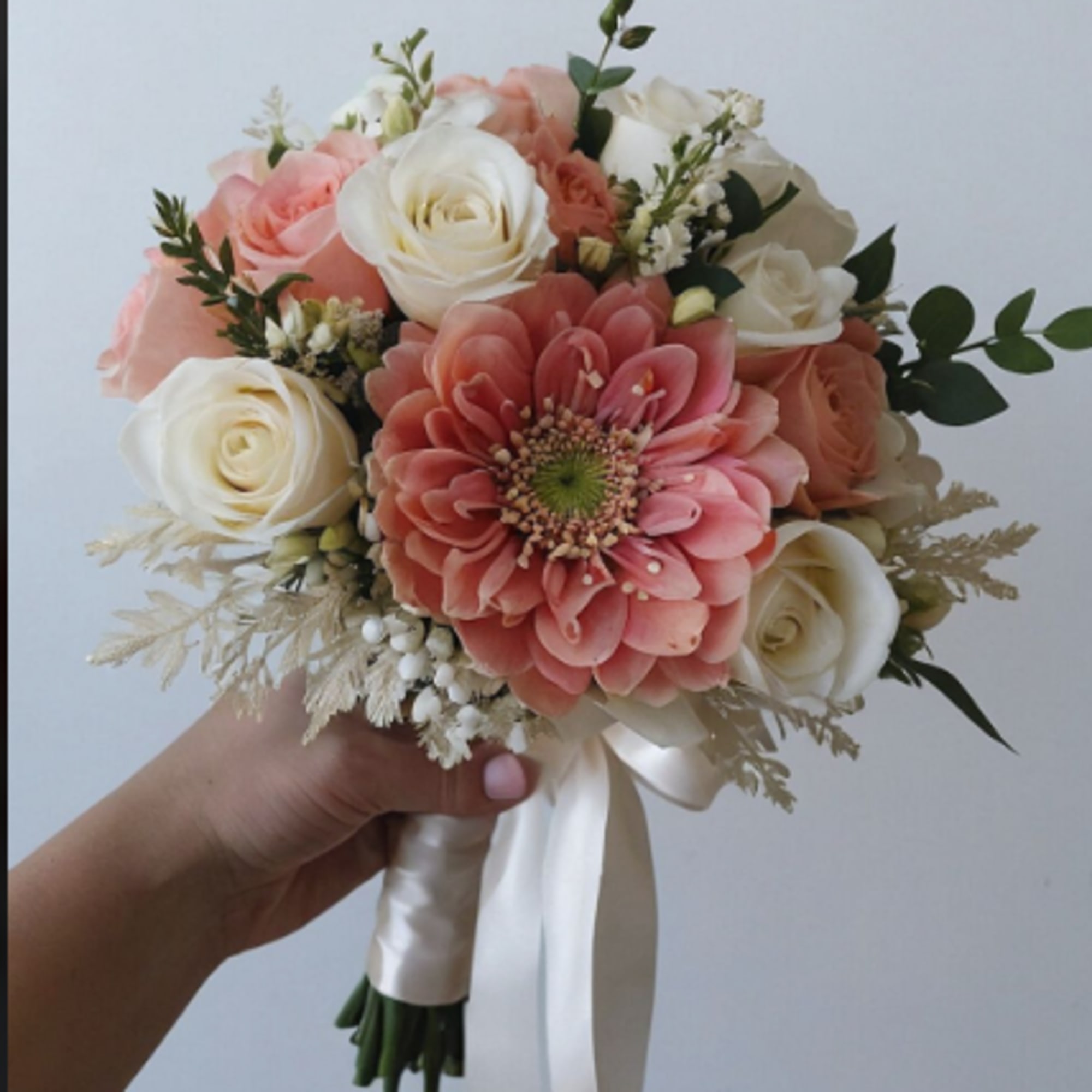 Handheld bouquet of pink and white roses with a large pink bloom