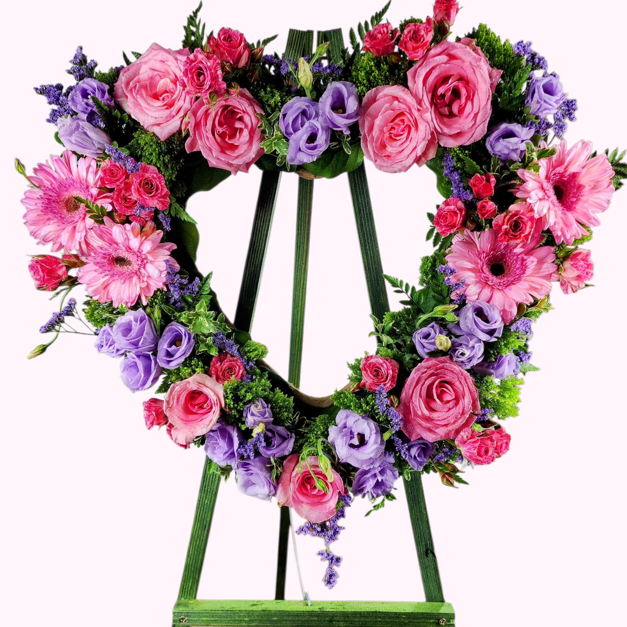 Heart-shaped floral wreath on a green easel with pink and purple blooms