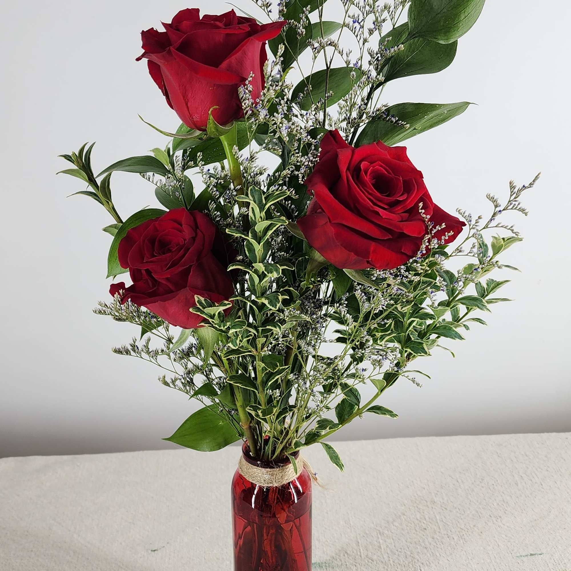 Elegant and timeless, this arrangement features three red roses accented with delicate