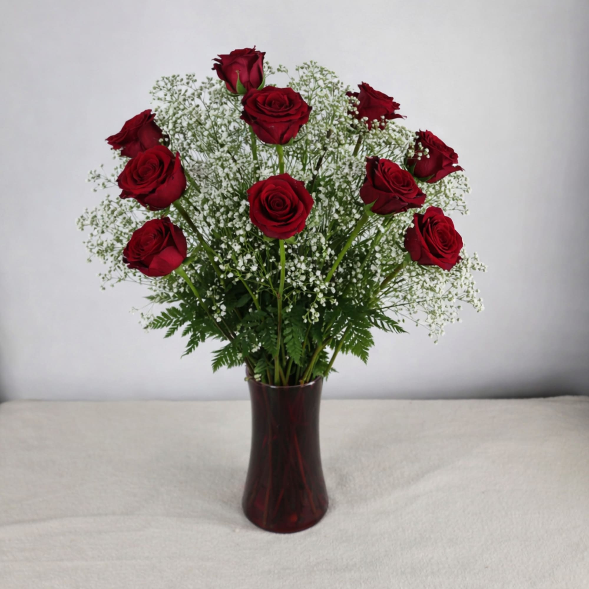 Red roses in a dark glass vase with white filler flowers