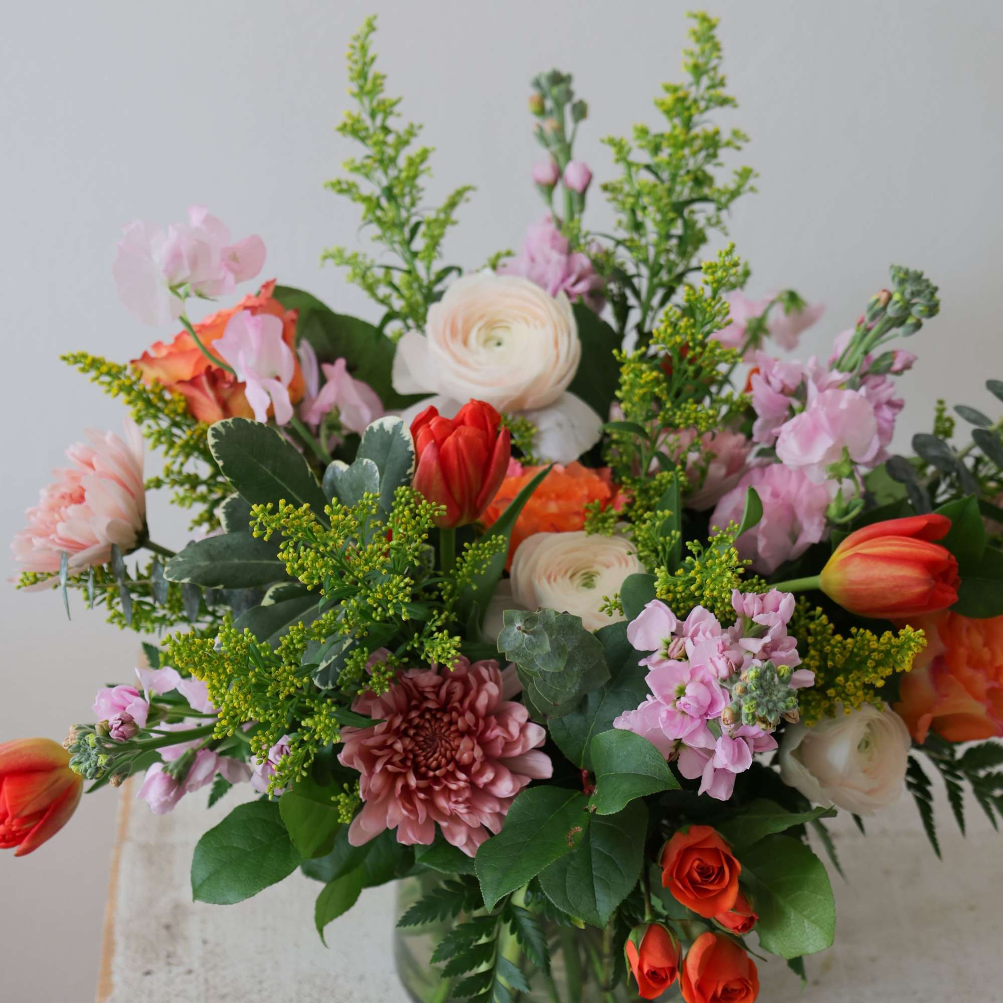 Mixed bouquet of pink, white, and orange flowers in a glass vase