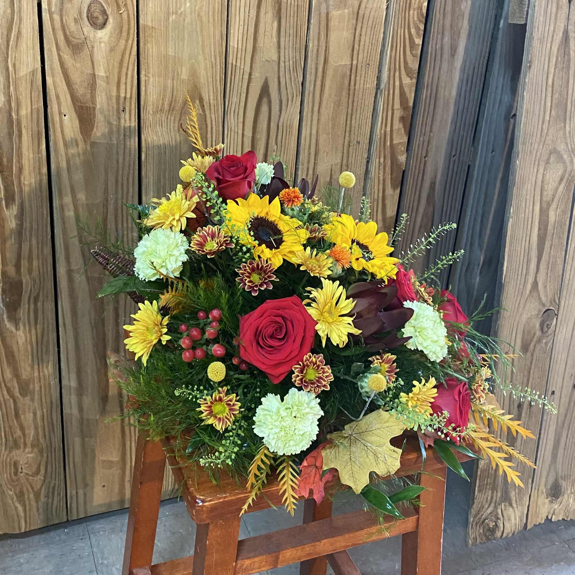 Bouquet of red roses, sunflowers, and mixed mums in a rustic arrangement