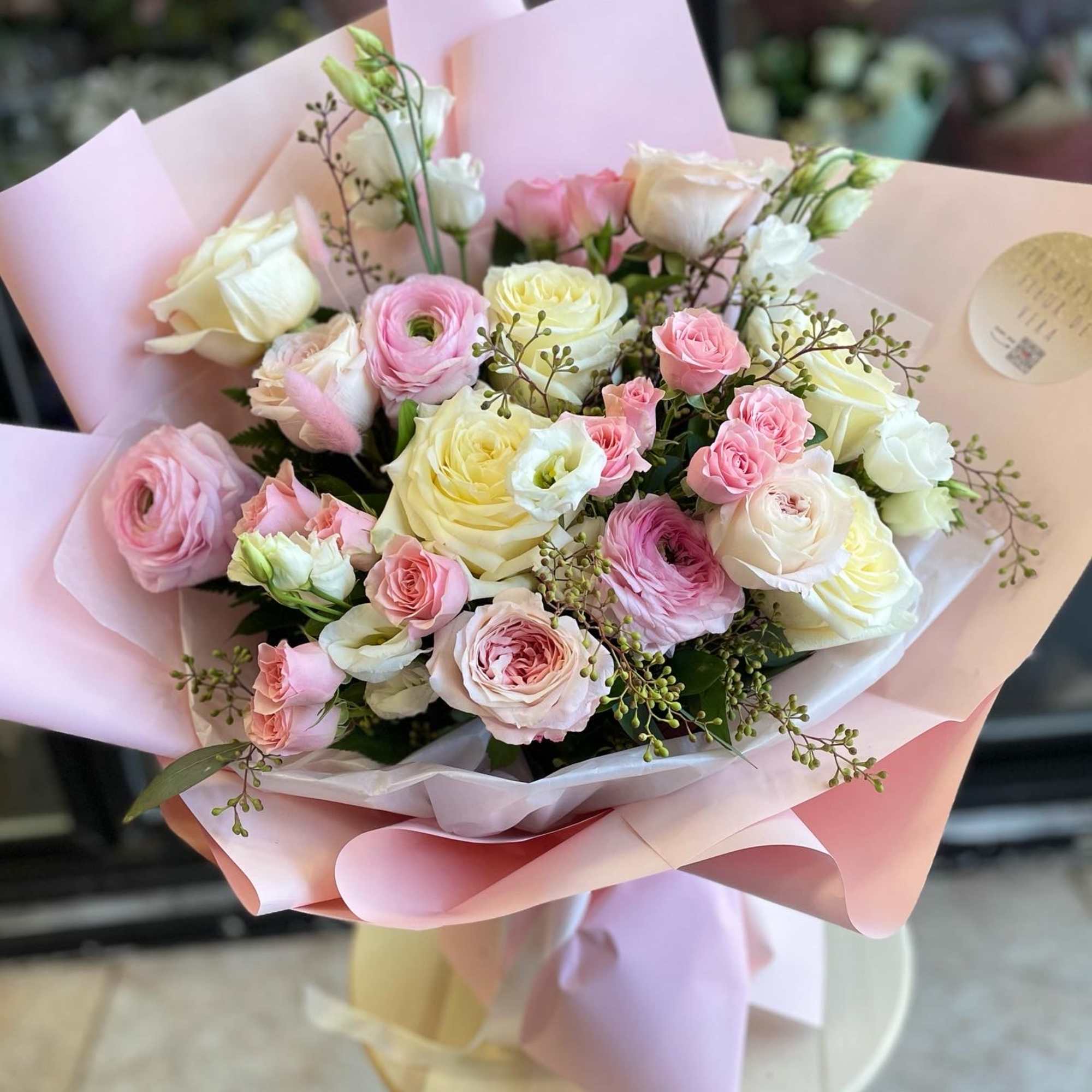 Bouquet of pink and white roses wrapped in pale pink paper