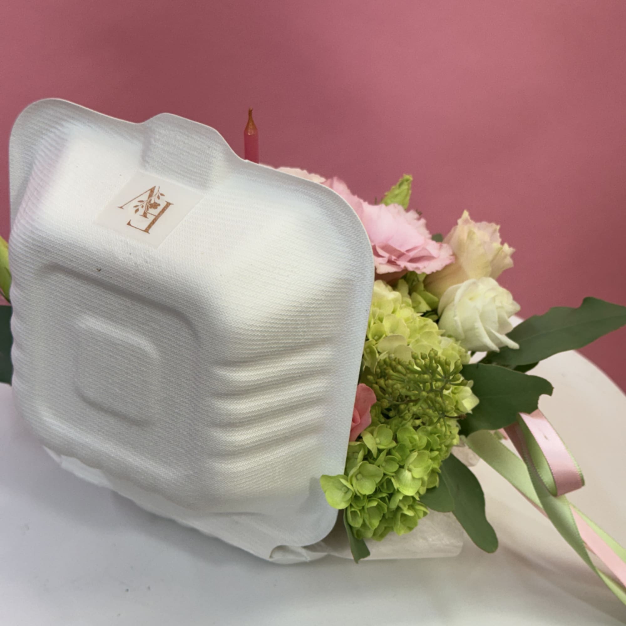 Wrapped bouquet of pink and white flowers with green hydrangeas