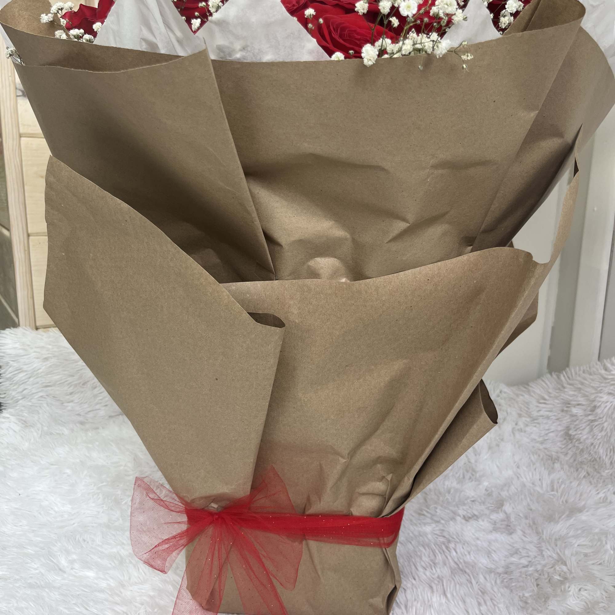 Bouquet of red roses with white baby's breath wrapped in brown paper