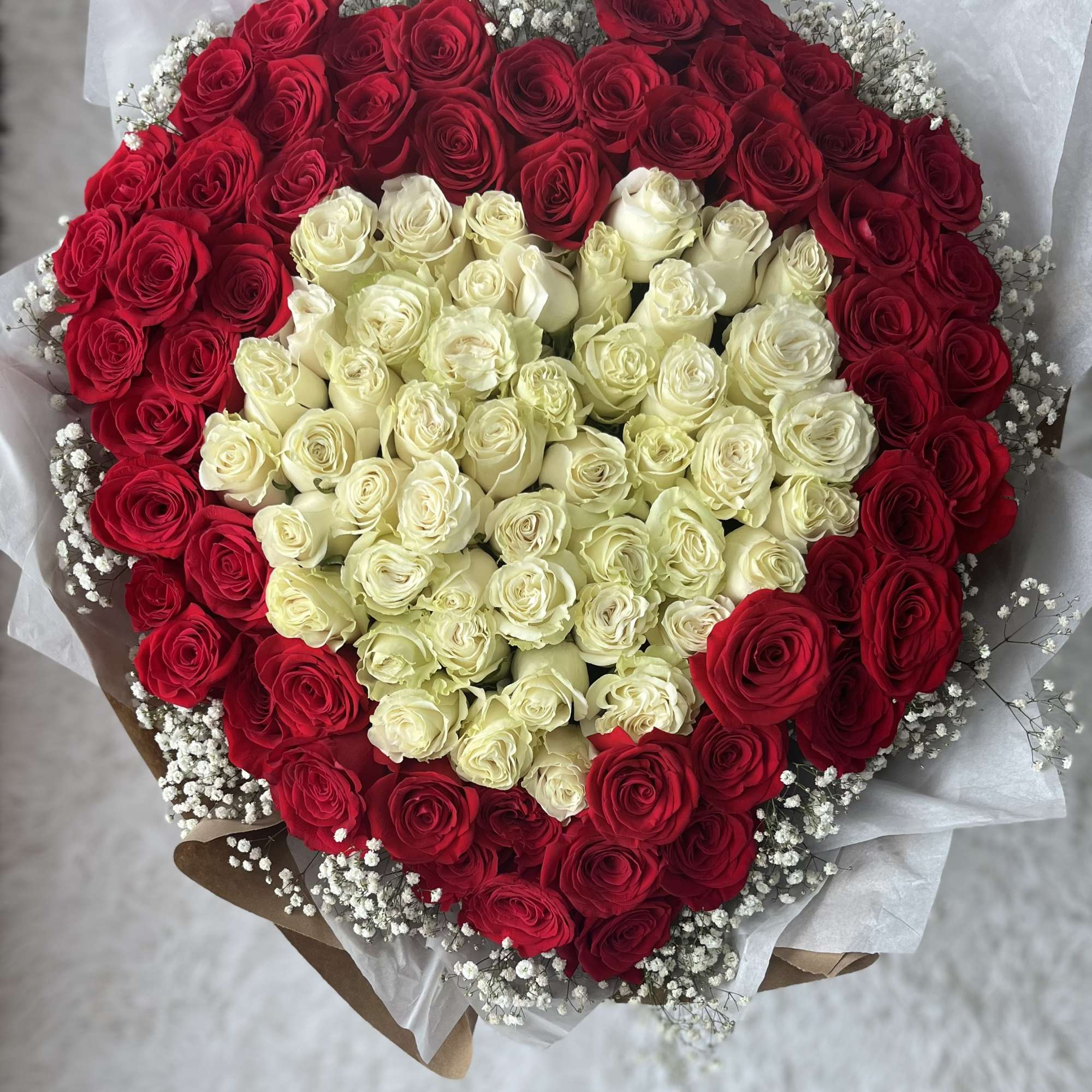 Heart-shaped bouquet of red and white roses with baby's breath