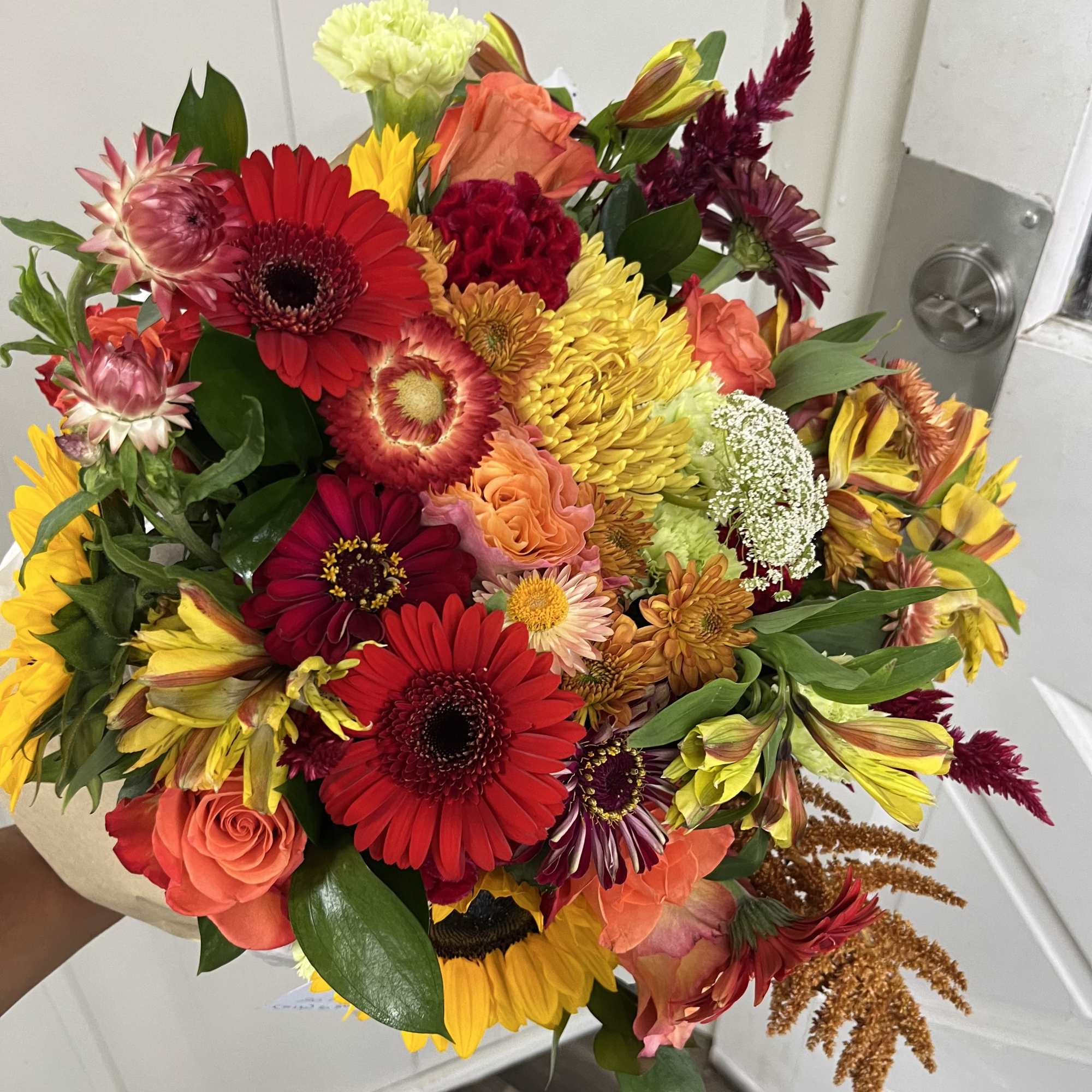 This arrangement is a wrapped bouquet with a mix of beautiful fall
