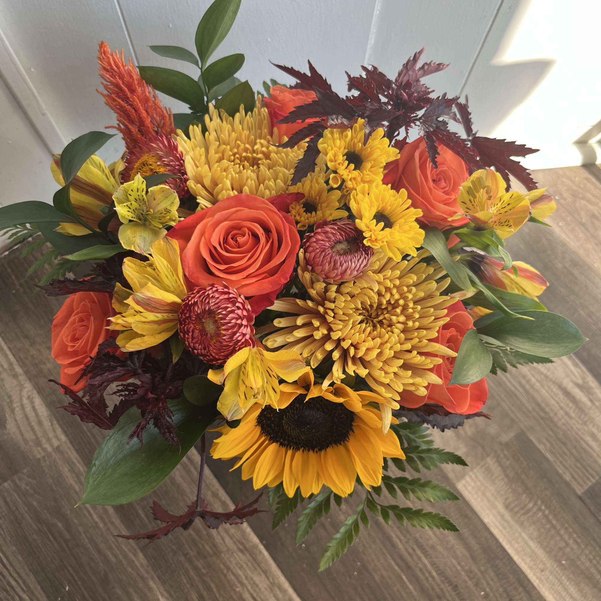 This arrangement is a wrapped bouquet with a mix of beautiful fall