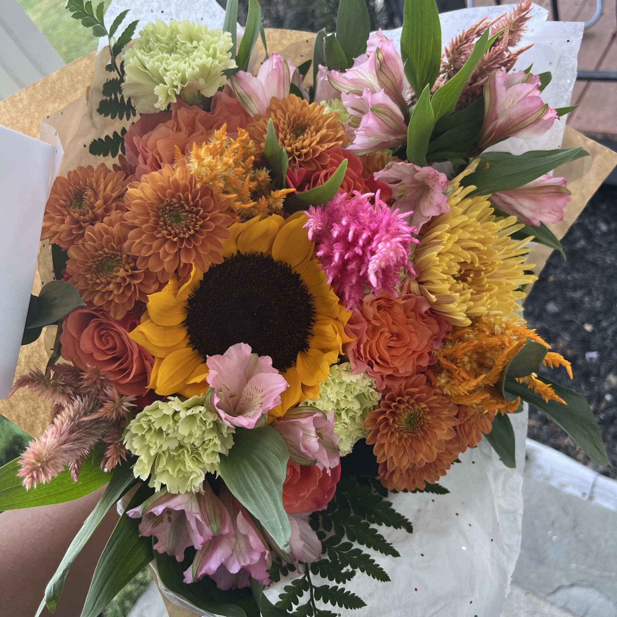This arrangement is a wrapped bouquet with a mix of beautiful fall
