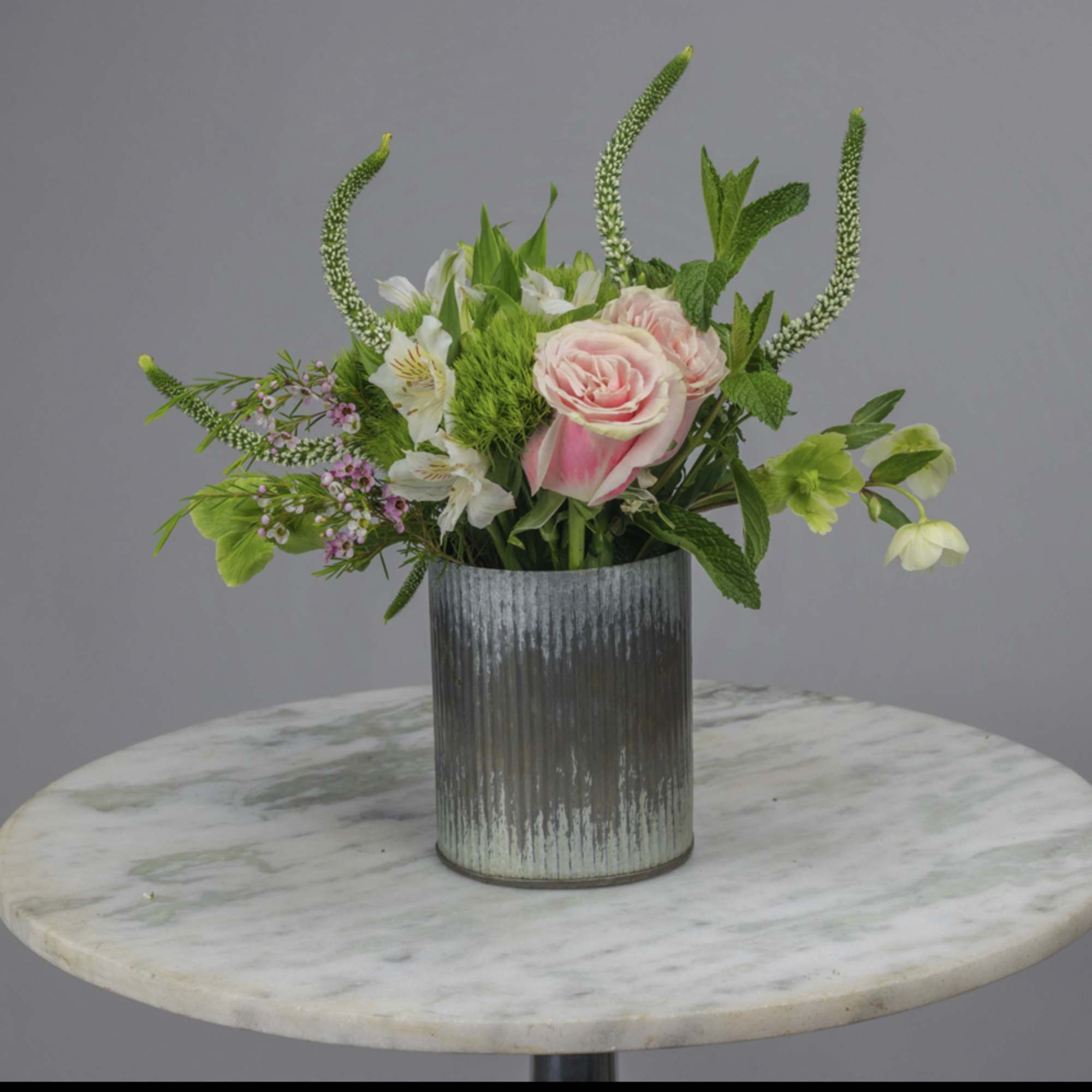 Pink roses and white flowers in a ribbed metal vase