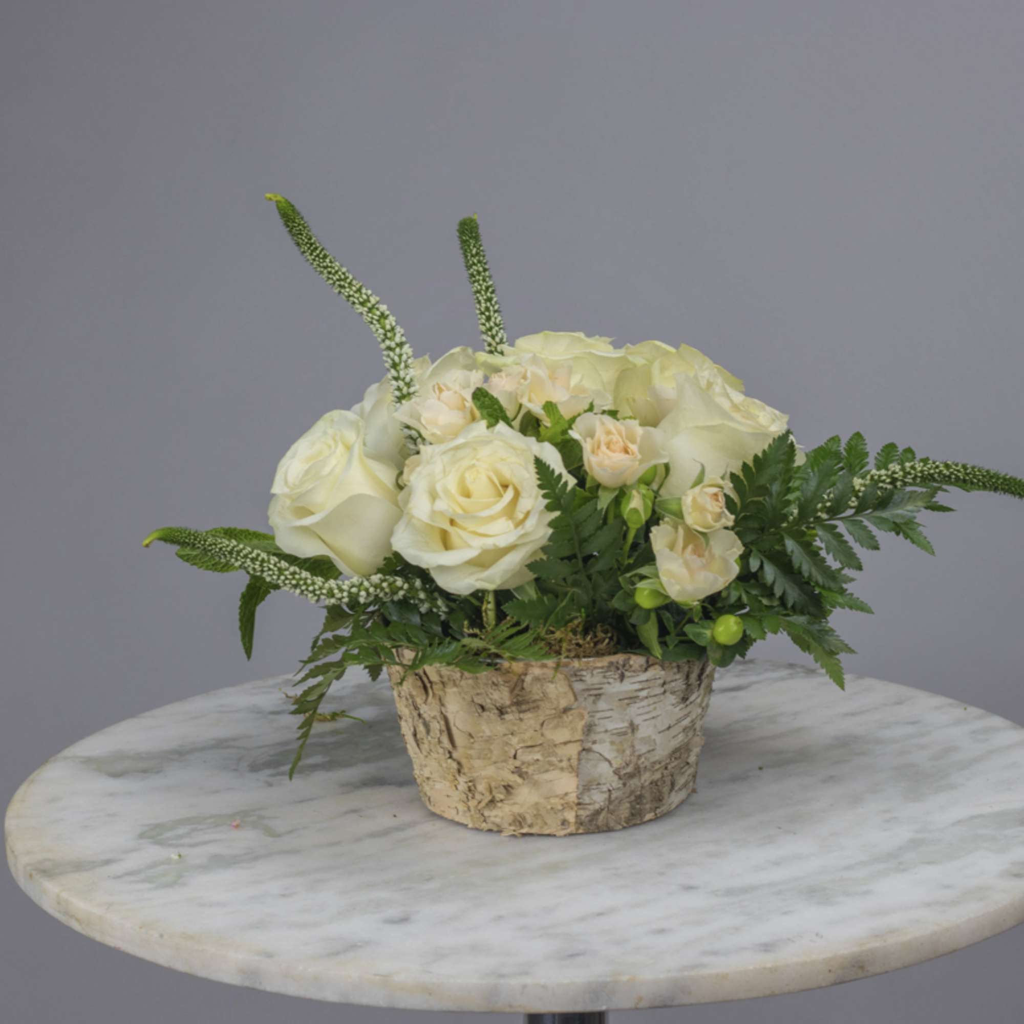 Cream rose arrangement in a birch bark container