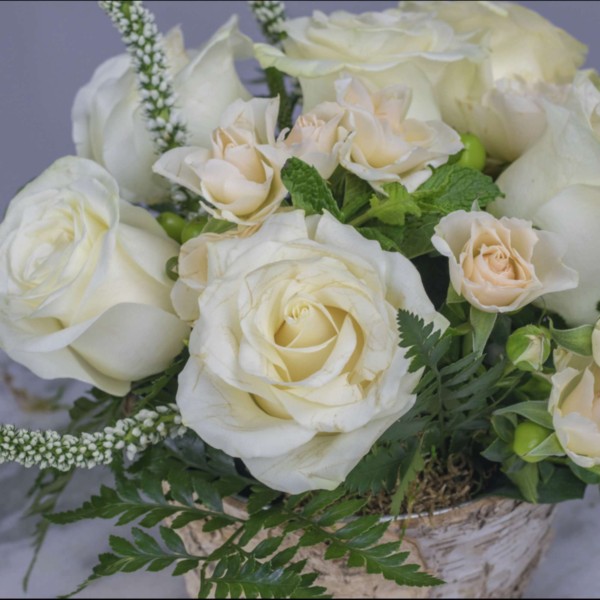Cream roses and peach spray roses in a birch basket