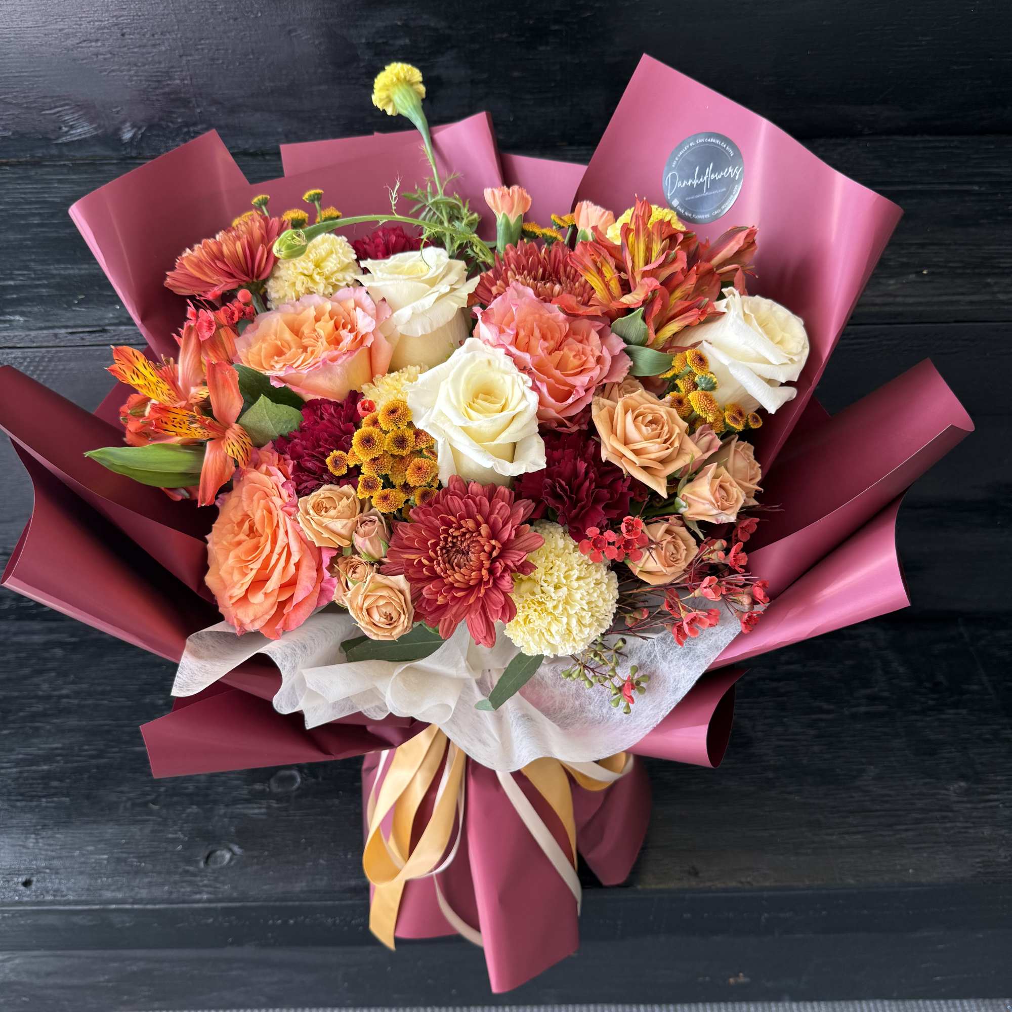 Mixed bouquet of roses, chrysanthemums, and alstroemeria wrapped in pink paper