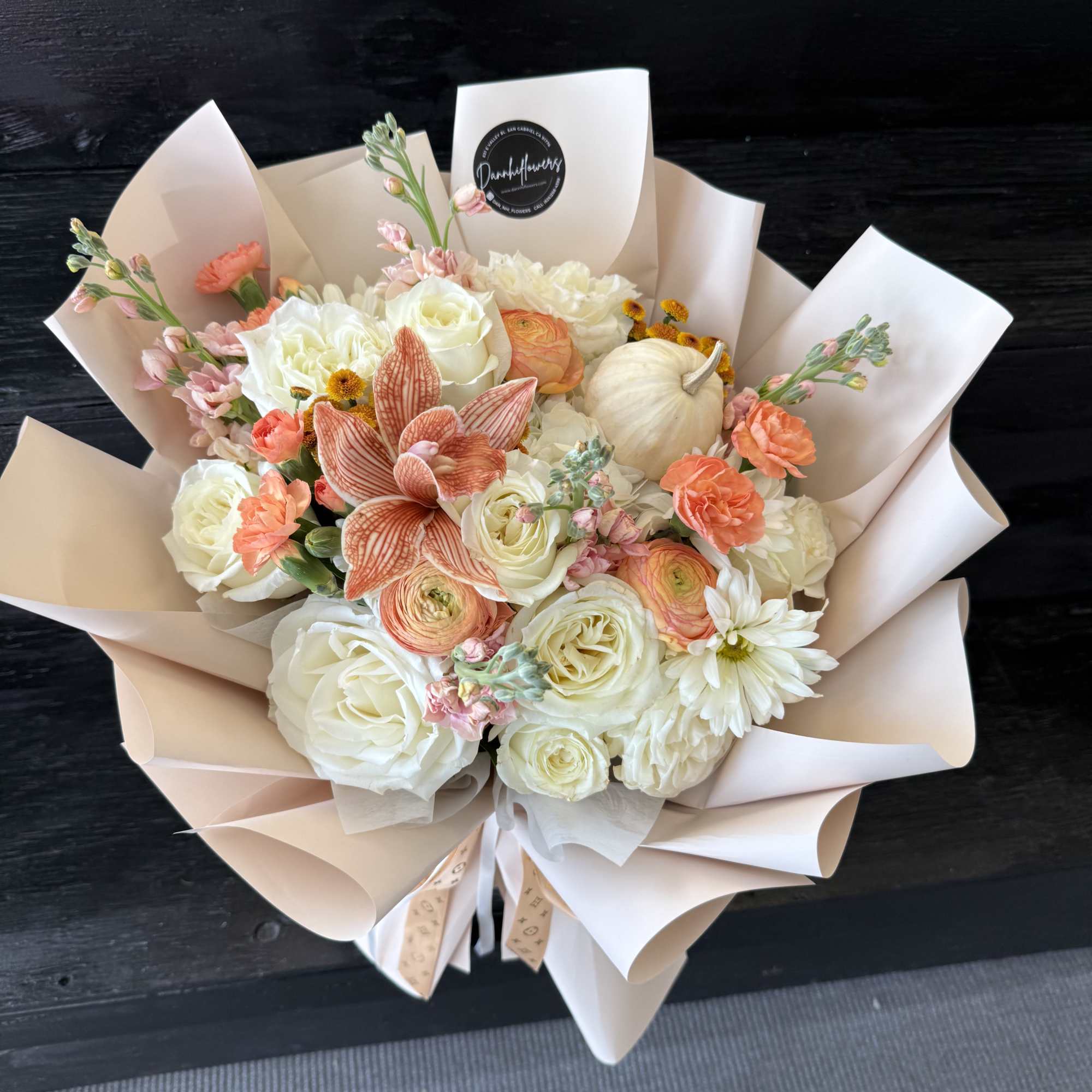 Bouquet of white and peach flowers wrapped in pale paper
