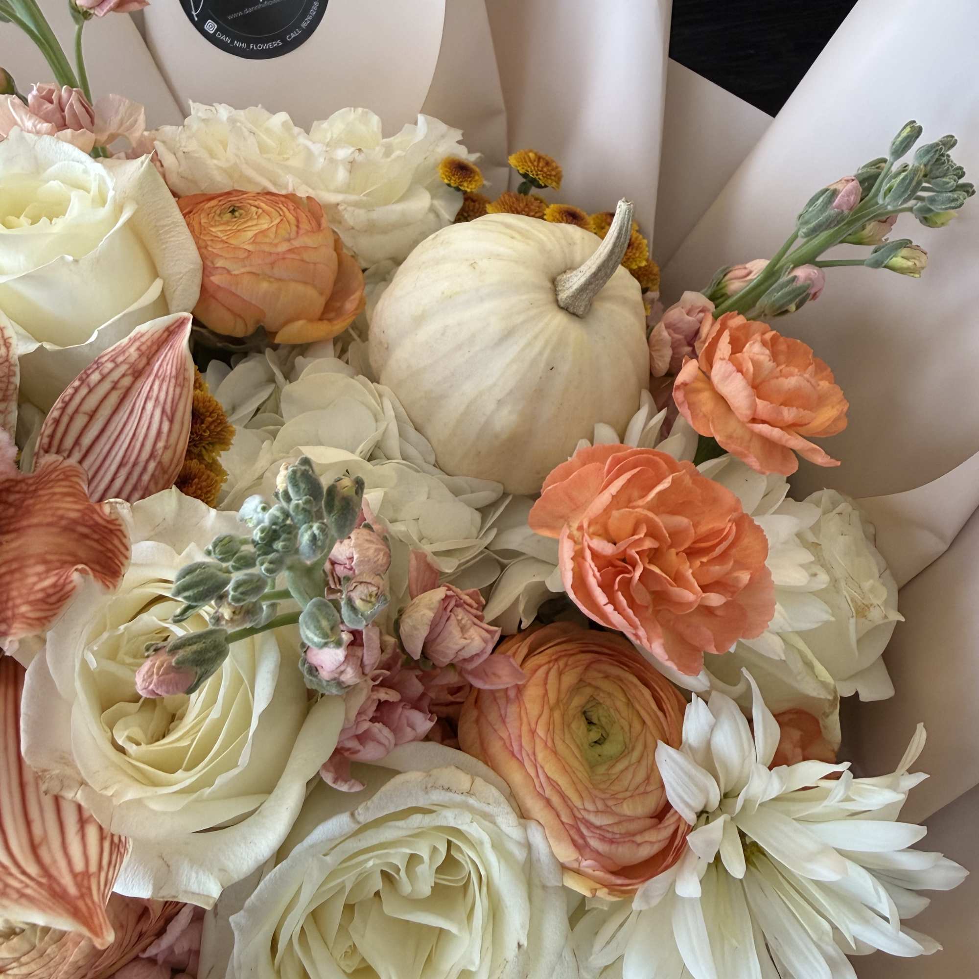 Bouquet of white and peach flowers with a small white pumpkin