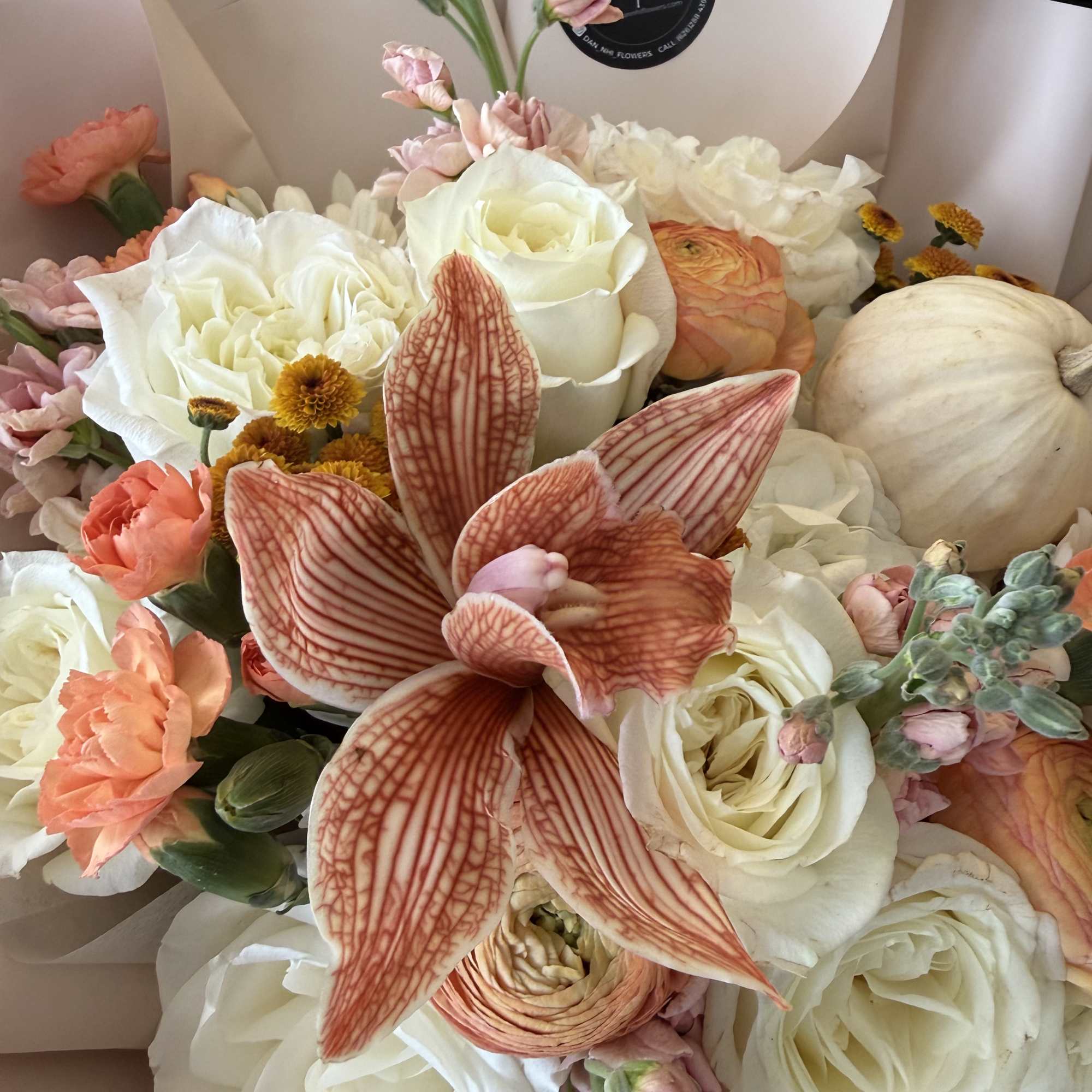 Bouquet of white roses, peach blooms, and a large striped orchid