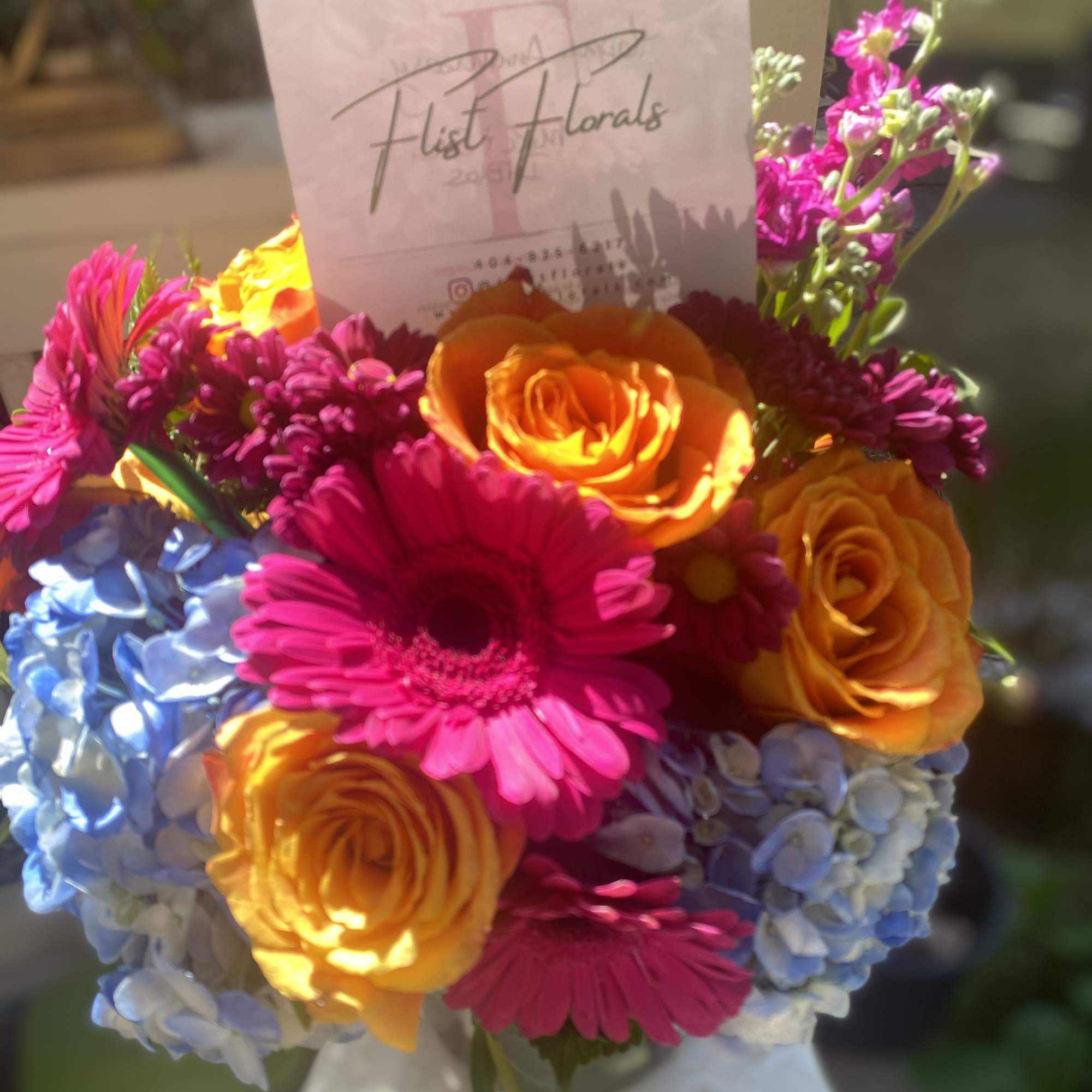 With the mixture of hot pink gerb daisies, orange roses and blue, photo 2 of 3