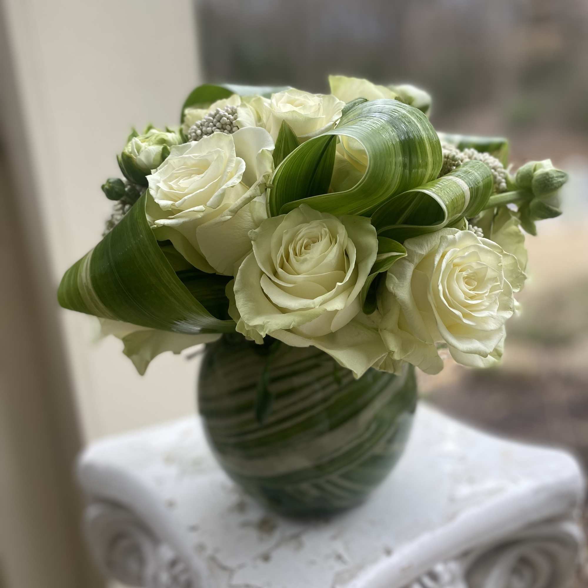 This arrangement is the perfect combination of white/ivory roses with a ribbon