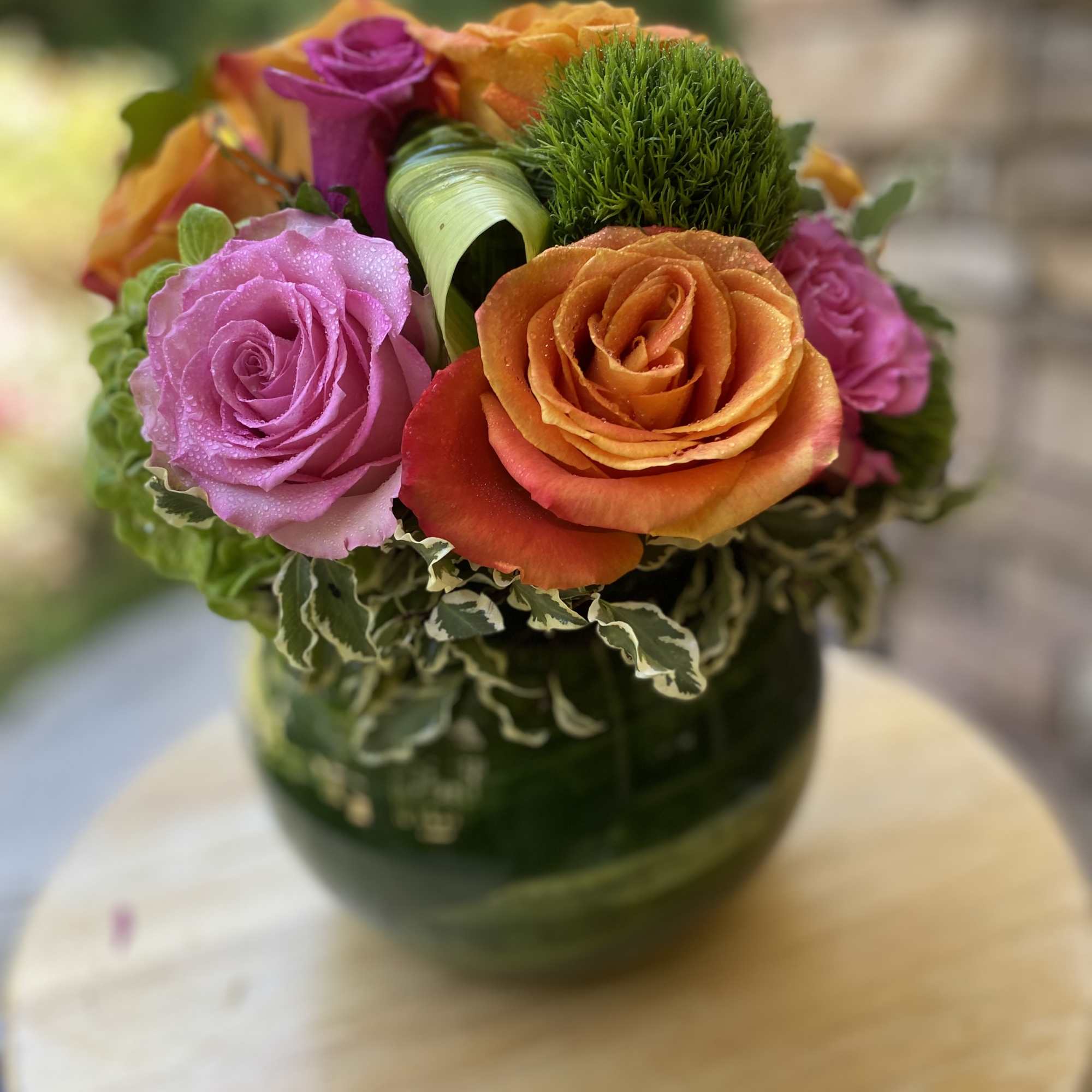 Brighten any space with this vibrant floral arrangement featuring bold orange and