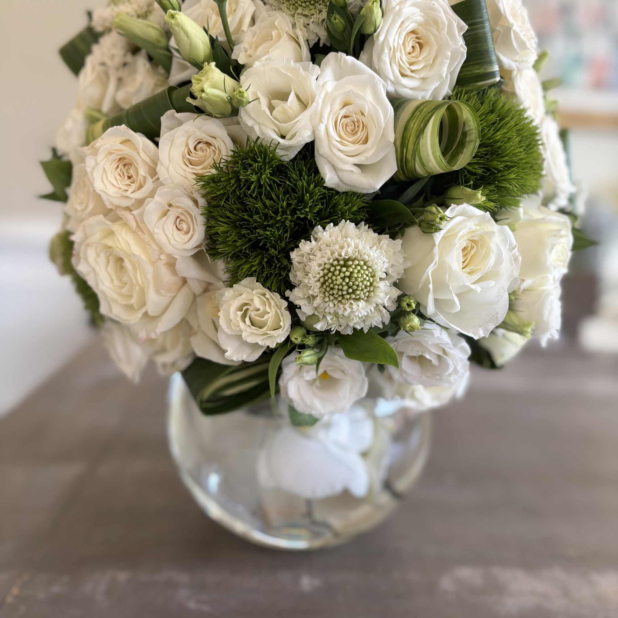 A medley of white mondial roses with luxury accent florals and Ti