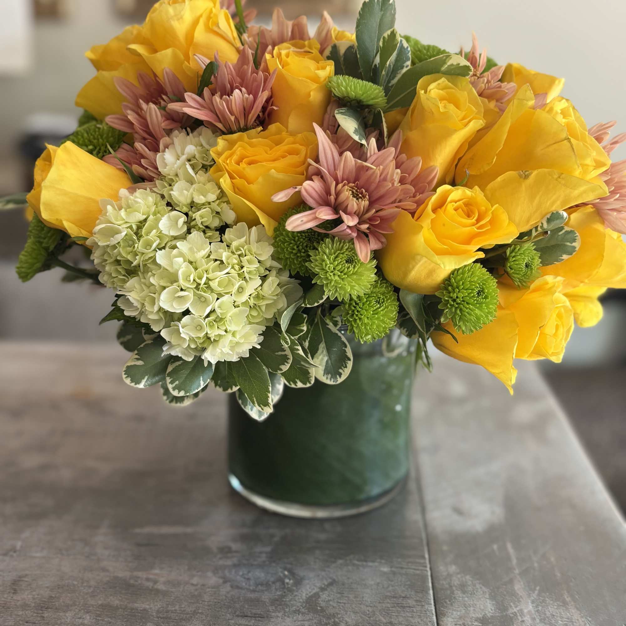 Yellow roses and hydrangeas are paired with peach flowering carnations and seasonal