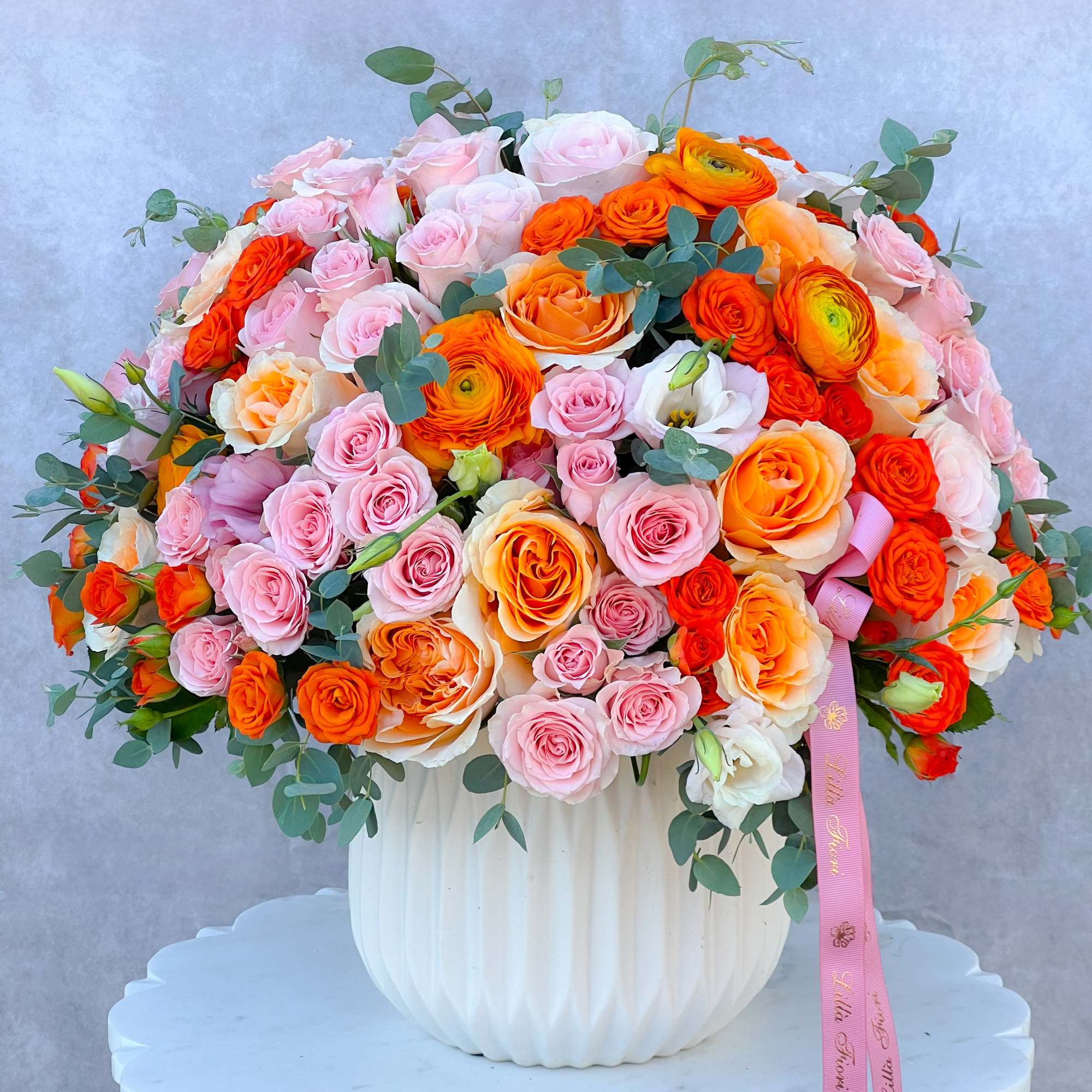 Large bouquet of pink and orange roses in a white vase