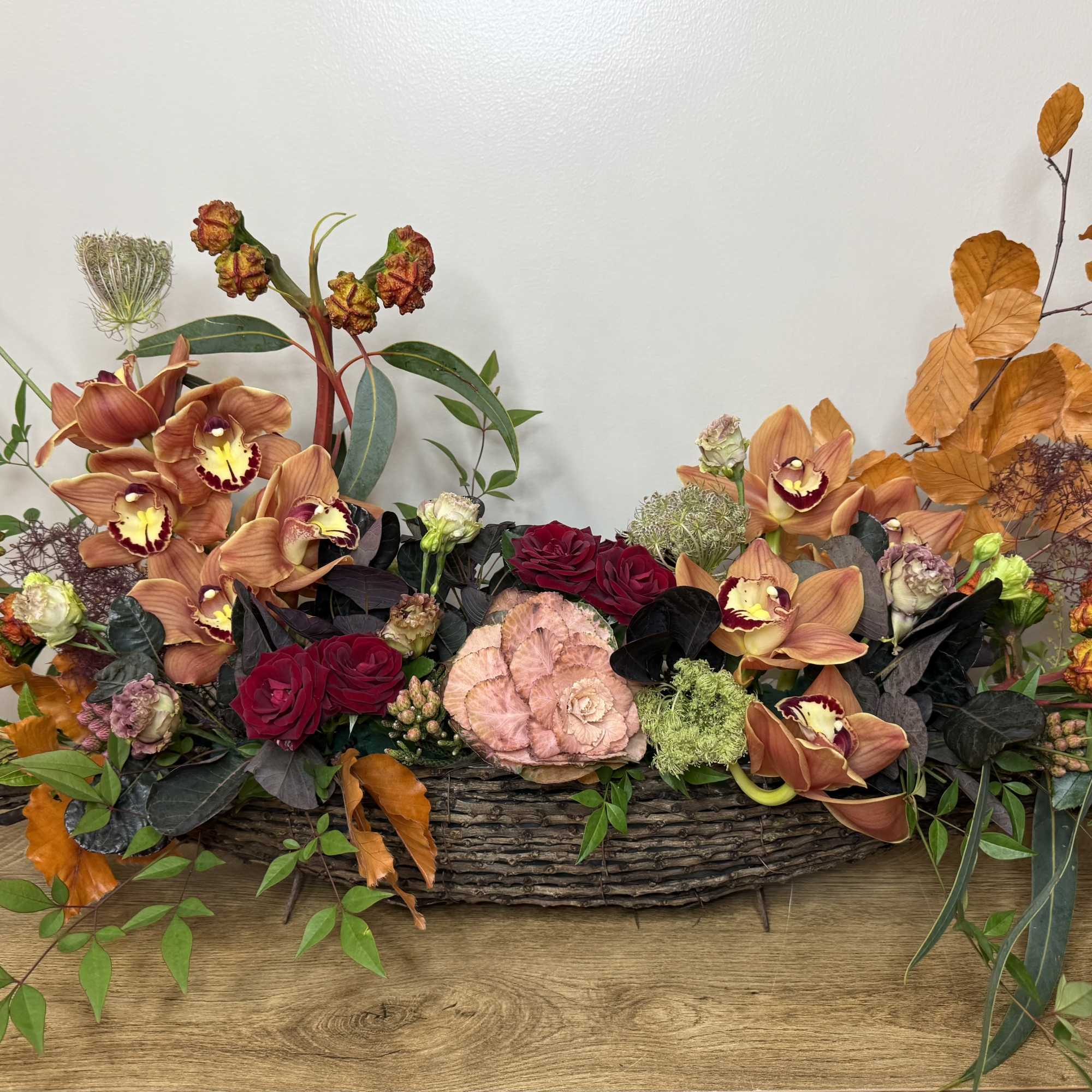 Low floral centerpiece with orchids and roses in a woven basket