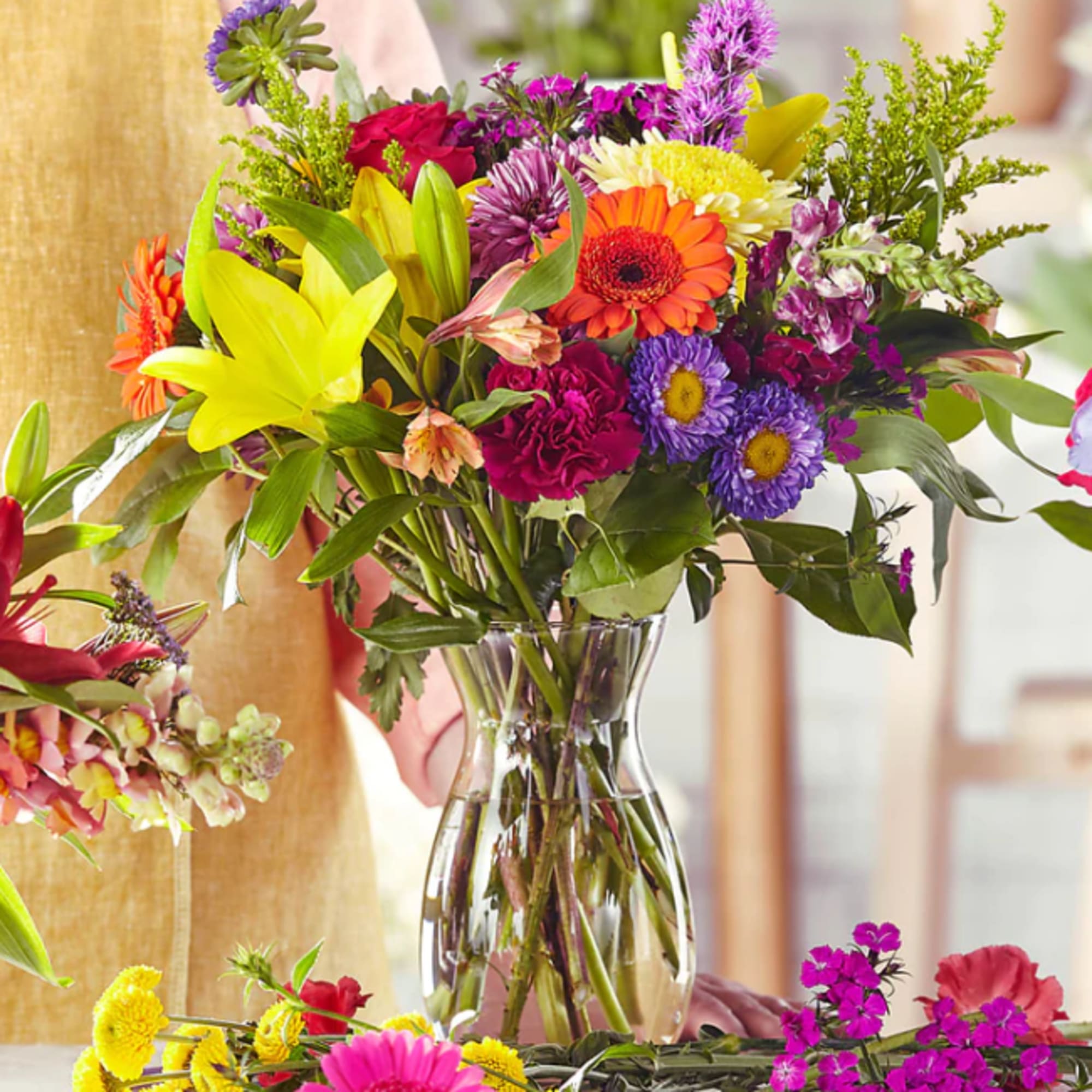 Colorful mixed bouquet in a clear glass vase with lilies and daisies