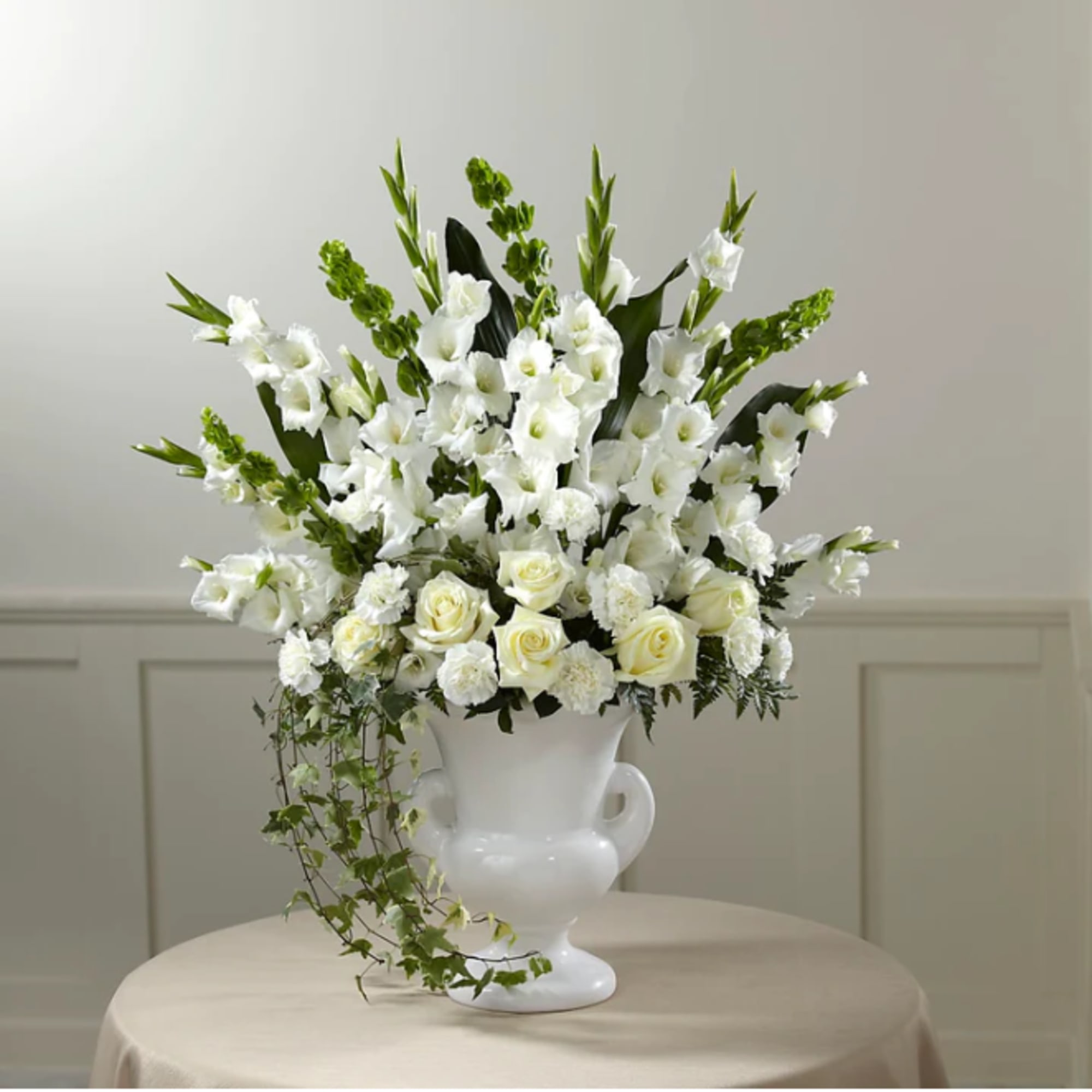 White floral arrangement in a white urn vase
