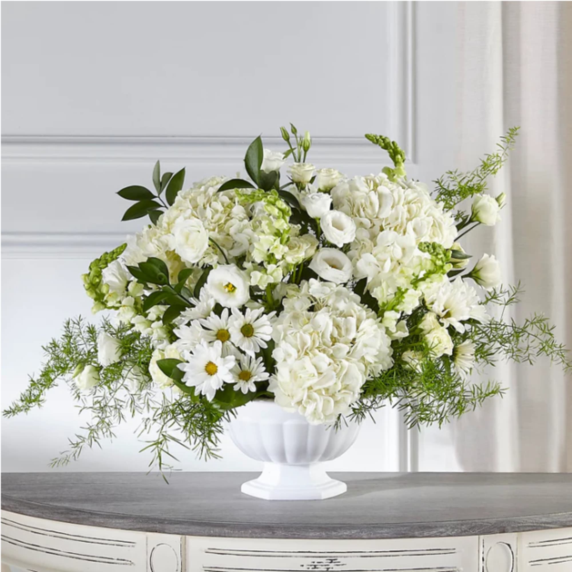 White floral arrangement in a white pedestal vase