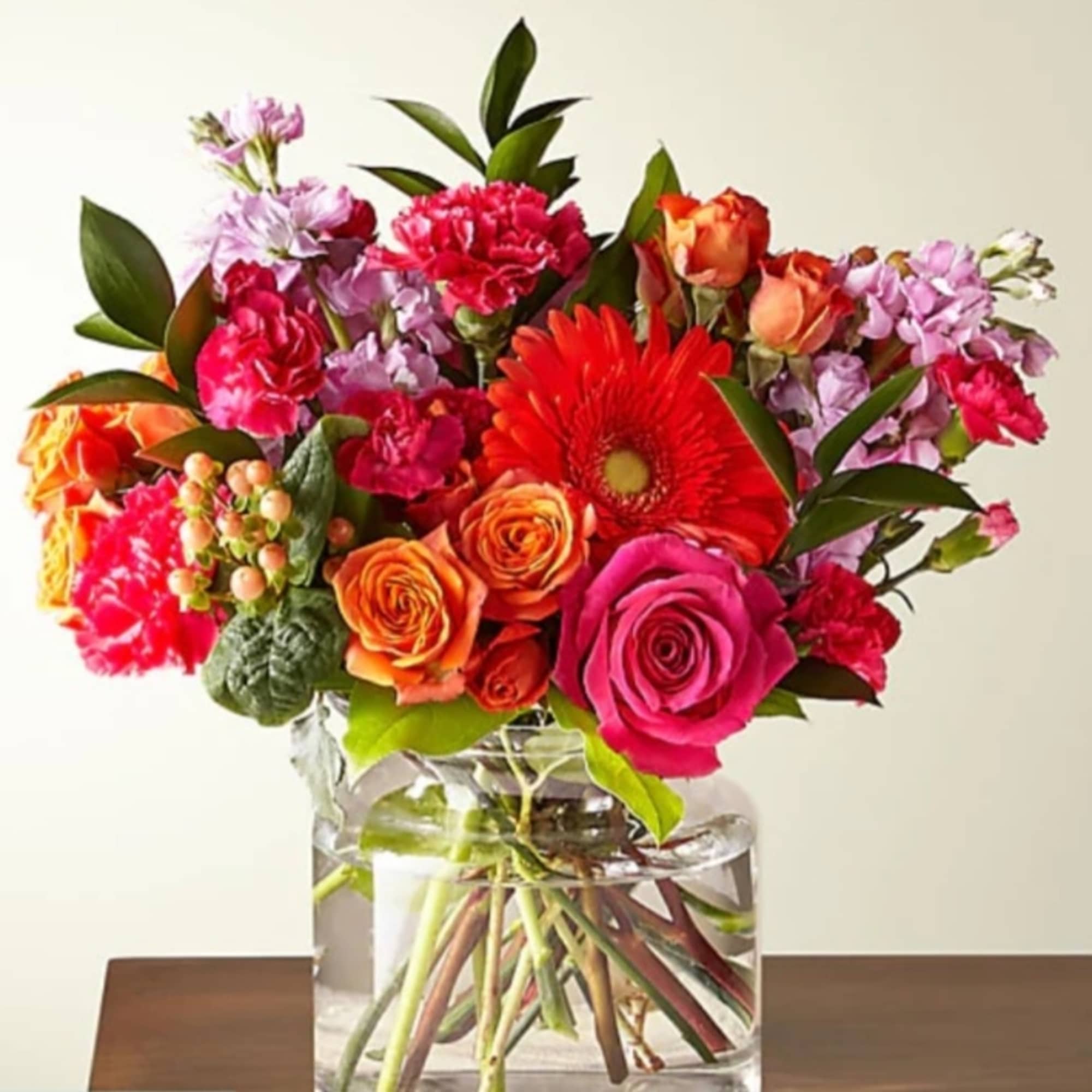 Bright mixed bouquet in a clear glass vase with roses and gerbera daisies
